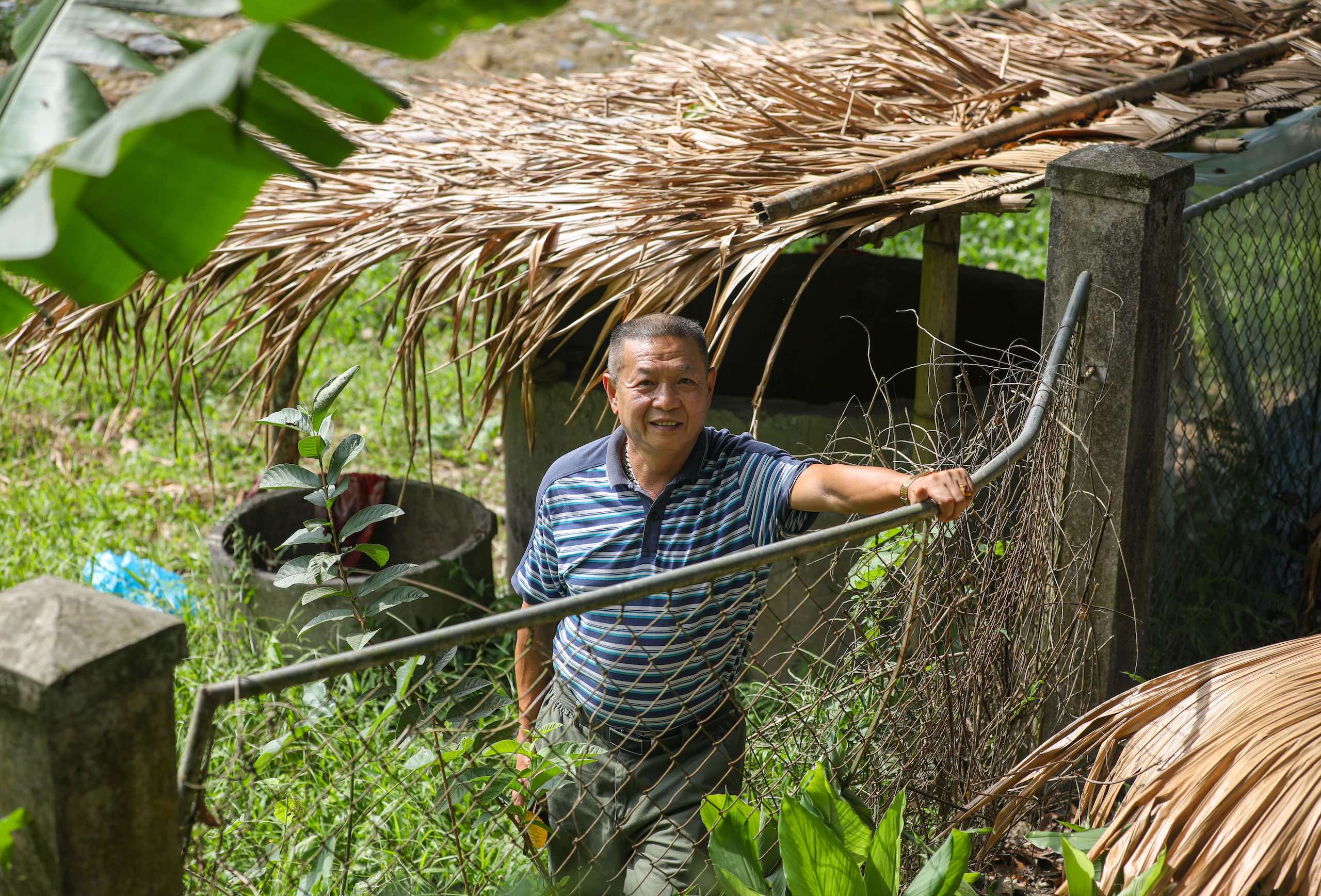 Vietnam park ranger leans against metal fence looking at the camera