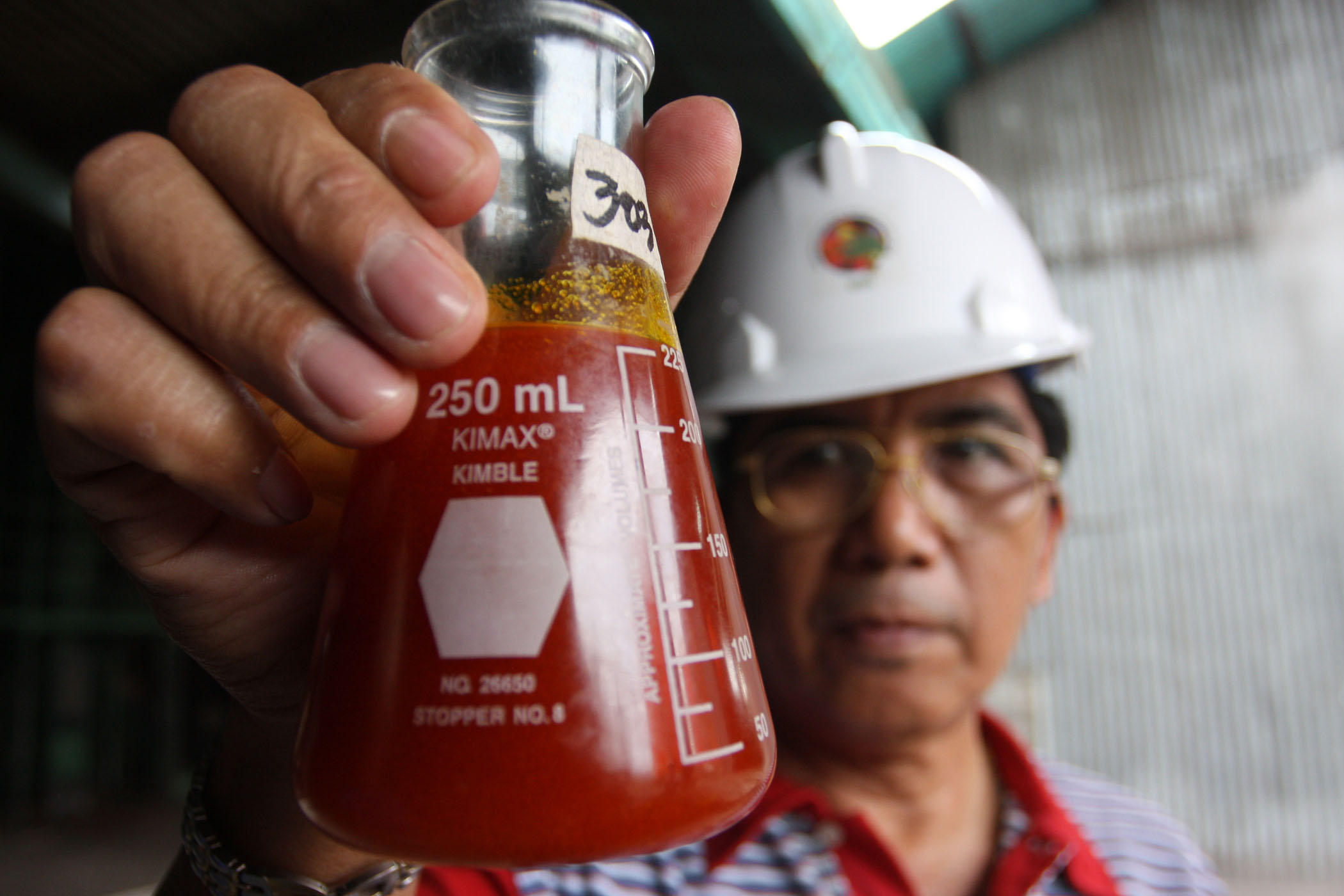 man holding 250mL glass conical flask filled with red liquid