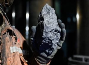 Person holding a lump of coal in a gloved hand