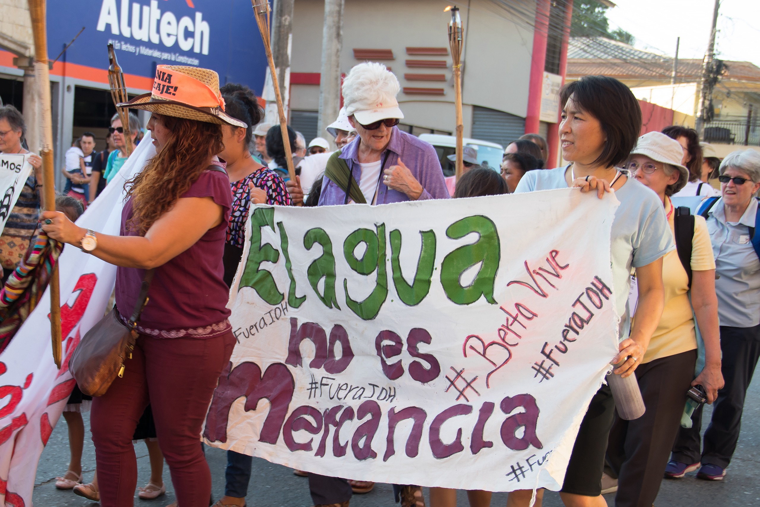 A group of people protesting, holding a whites sheet with writing on it