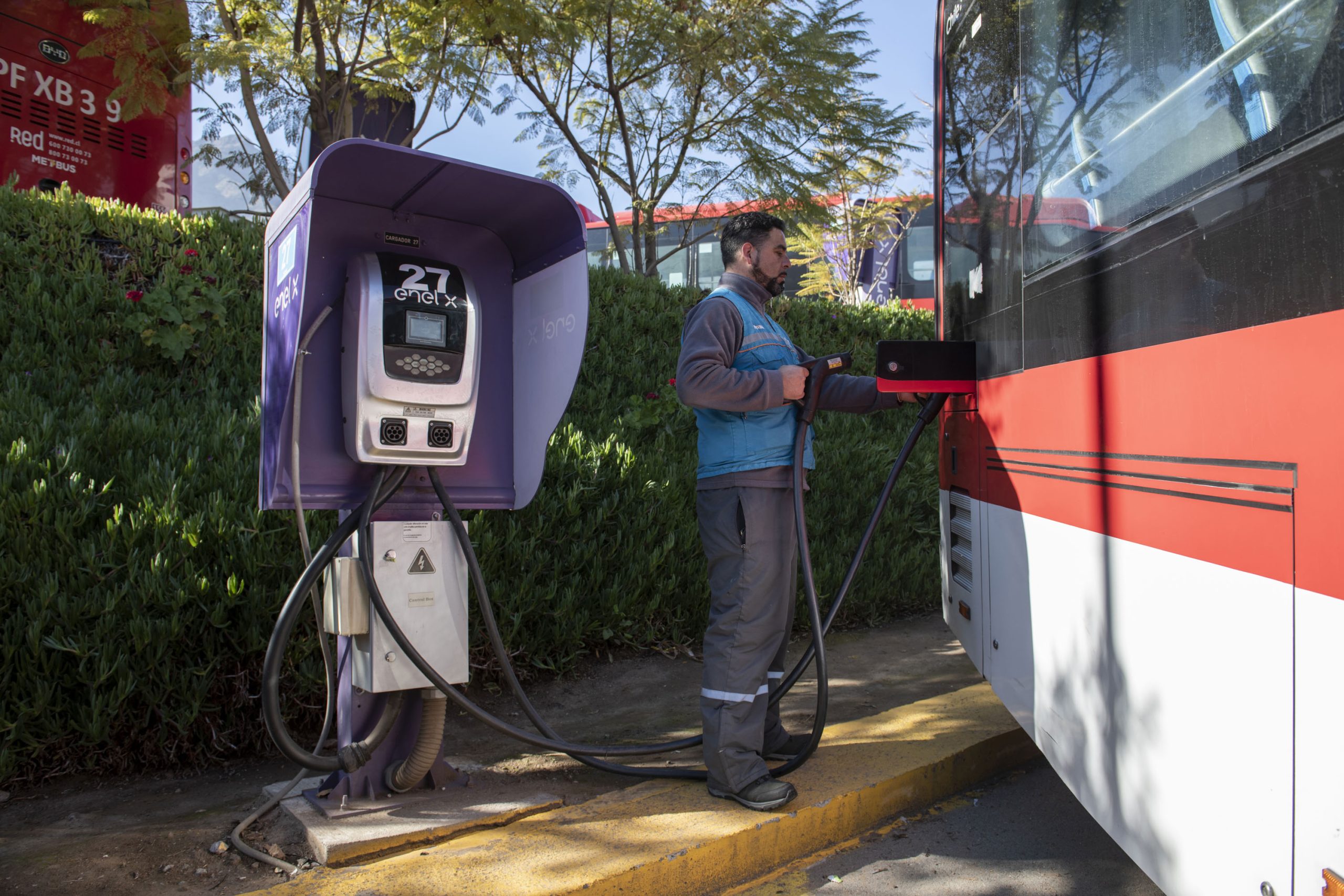 man connecting electric bus to charging station