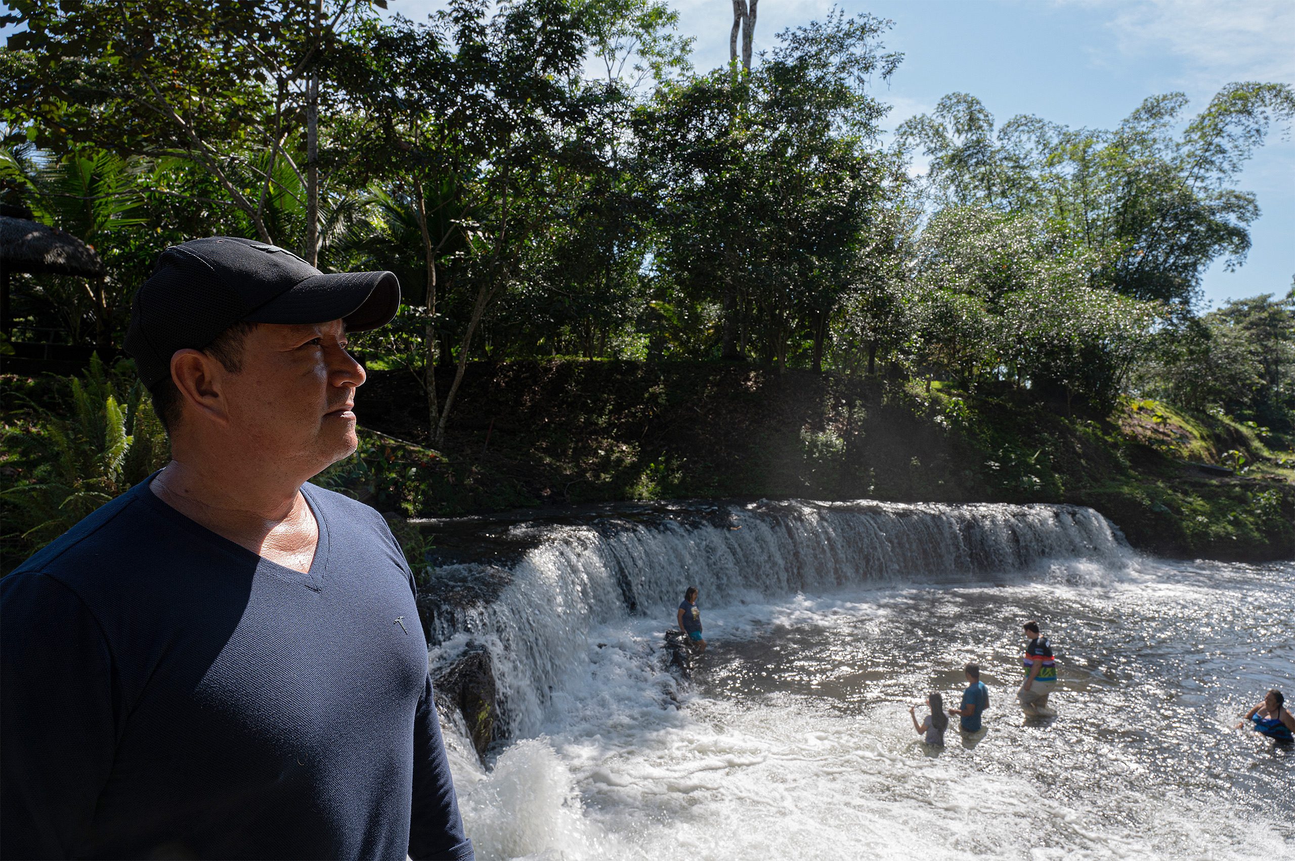 People in pool below waterfall 