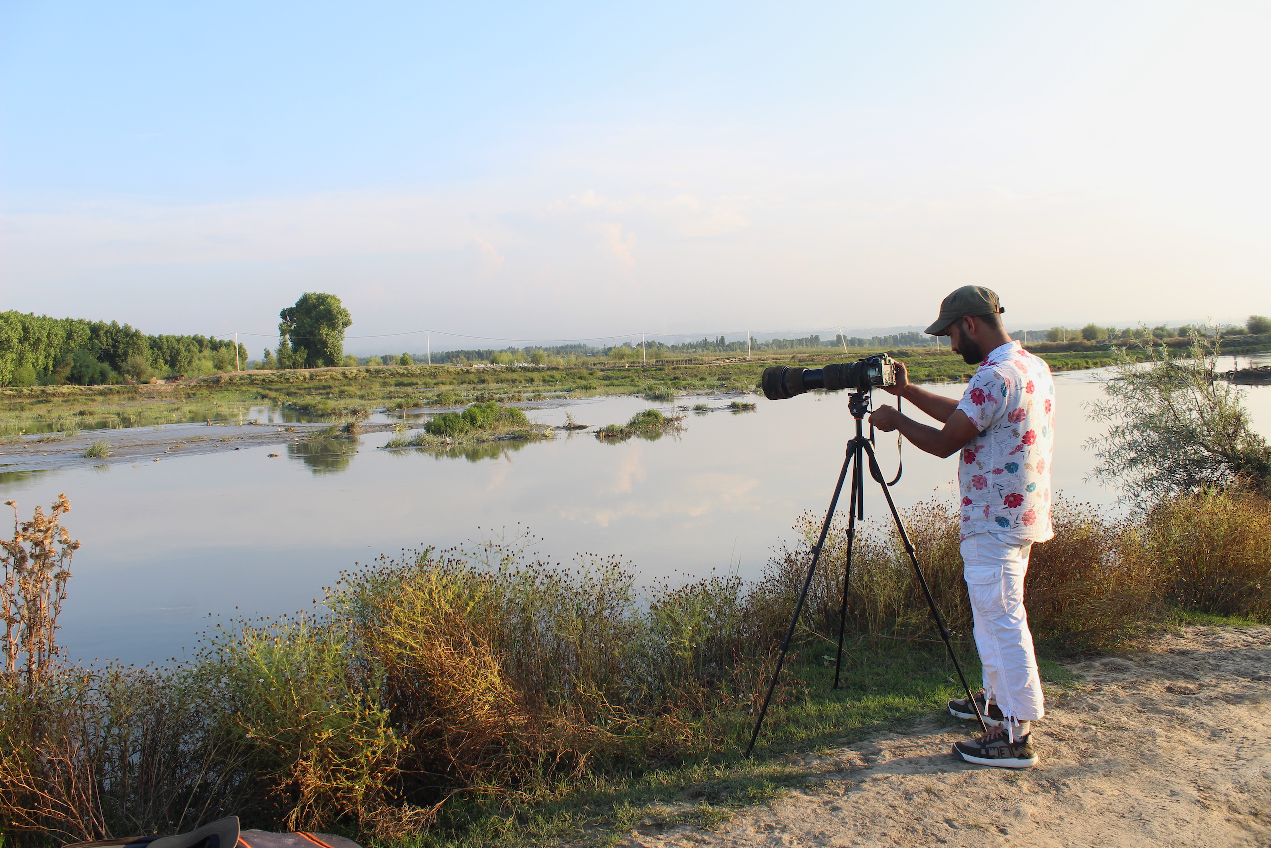 A man birdwatching through his camera in a wetland