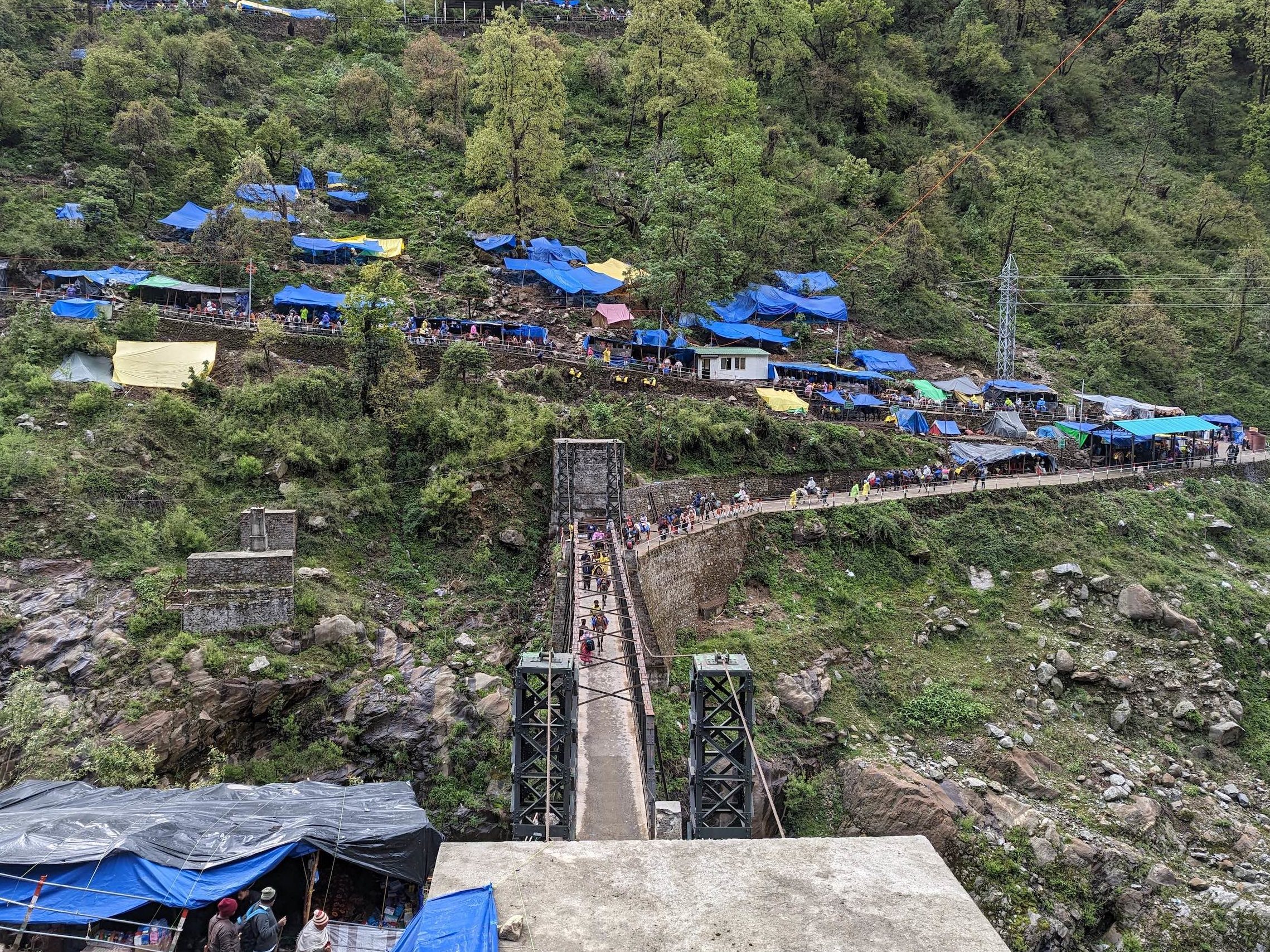 Blue-roofed buildings in a green mountainous area, bridge over ravine