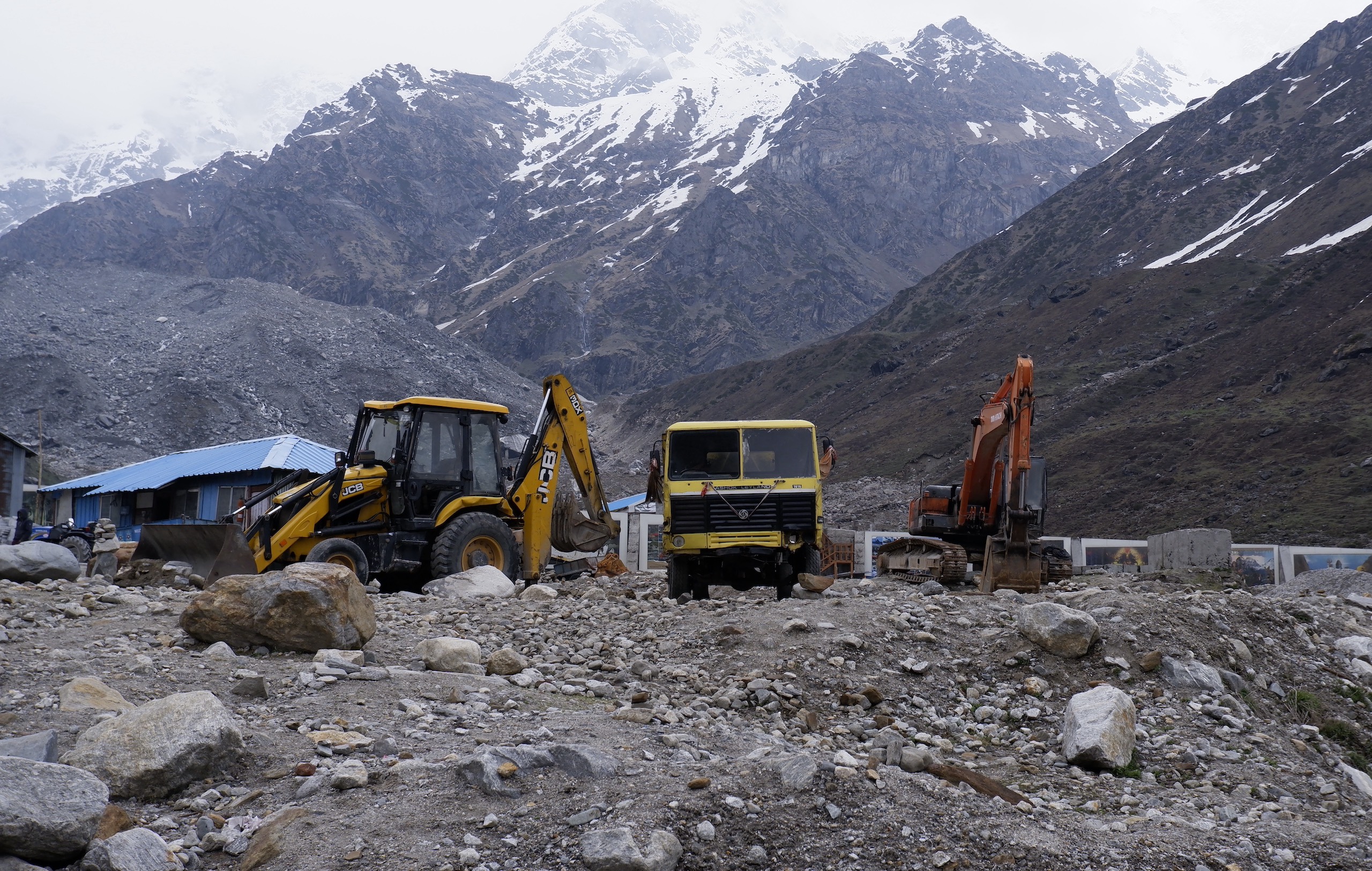 Two construction vehicles with snowy mountains in background