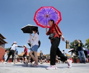 women holding umbrellas to block the sun in a hot day in beijing