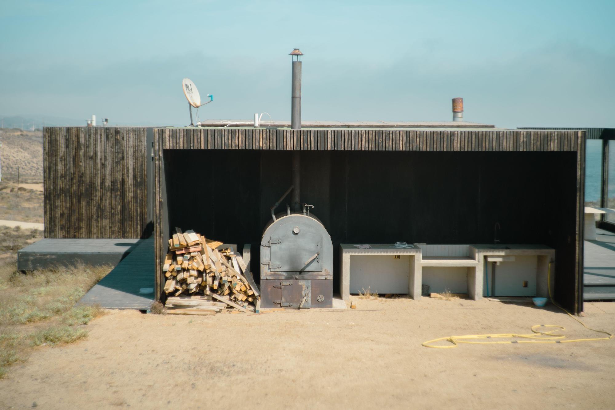 A rustic wood oven with stacks of firewood.