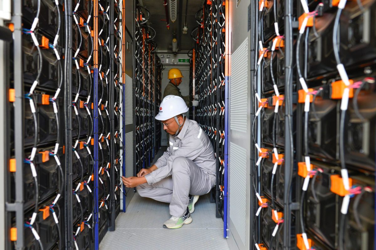 man kneeling between rows of power cells