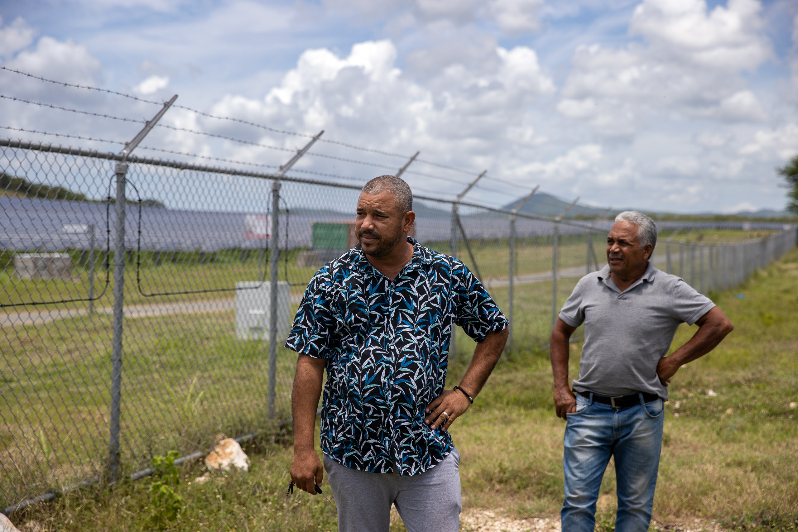 dos hombres de pie al lado de una larga valla metálica