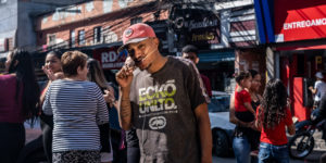 <p>Cleiton Araújo eats a churrasquinho beef kebab on the streets of the Paraisópolis favela in São Paulo, Brazil. The narrow streets of this neighbourhood often fill with smoke from barbecue grills, but consumption varies depending on changes in beef prices. (Image: Dan Agostini / Diálogo Chino)</p>