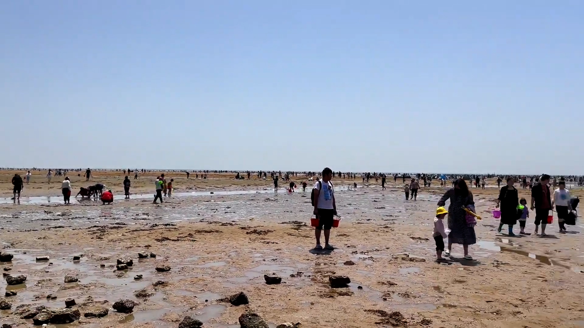 groups of people standing on a flat beach