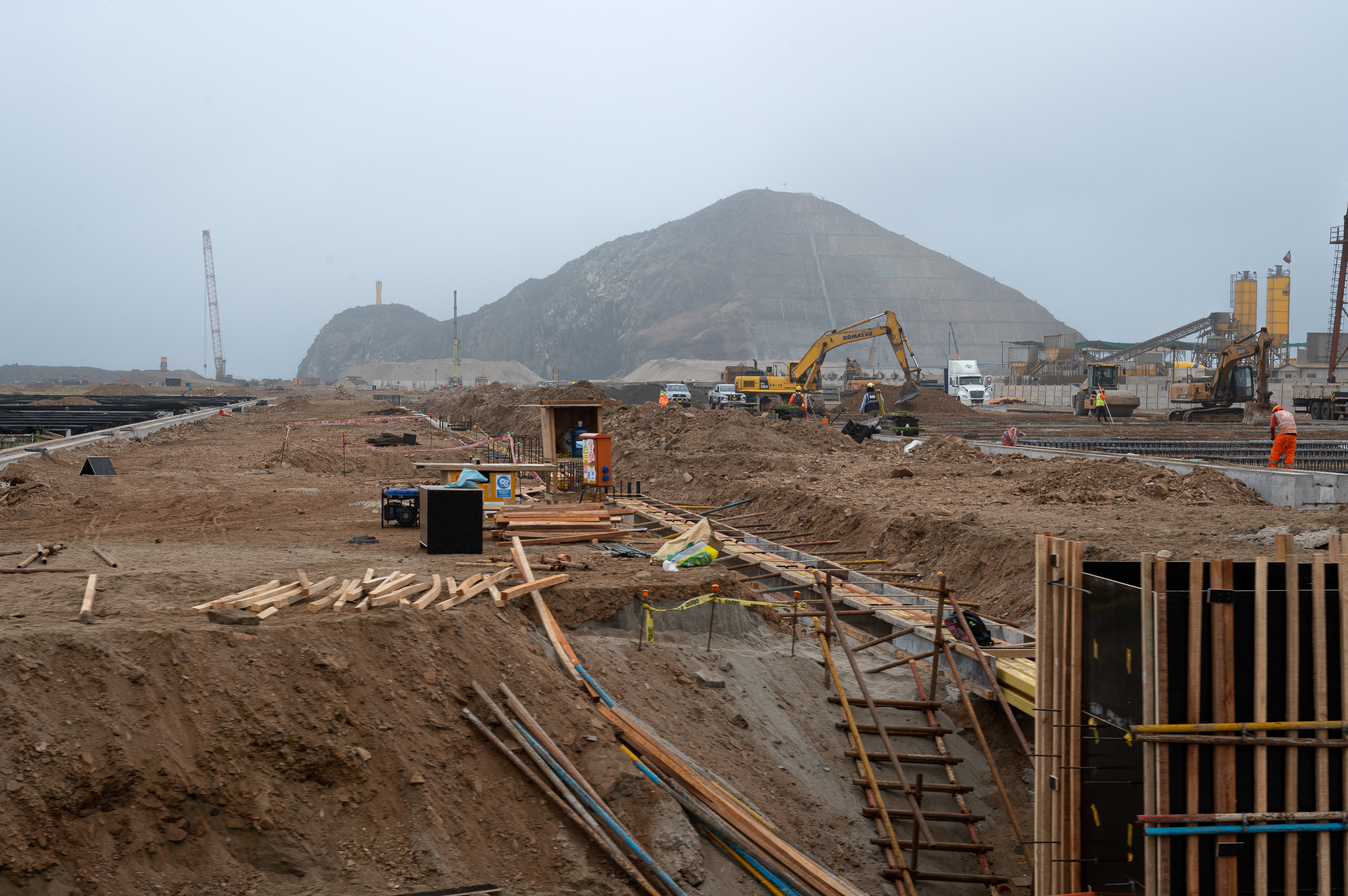 maquinaria en una zona de construcción, y un cerro detrás