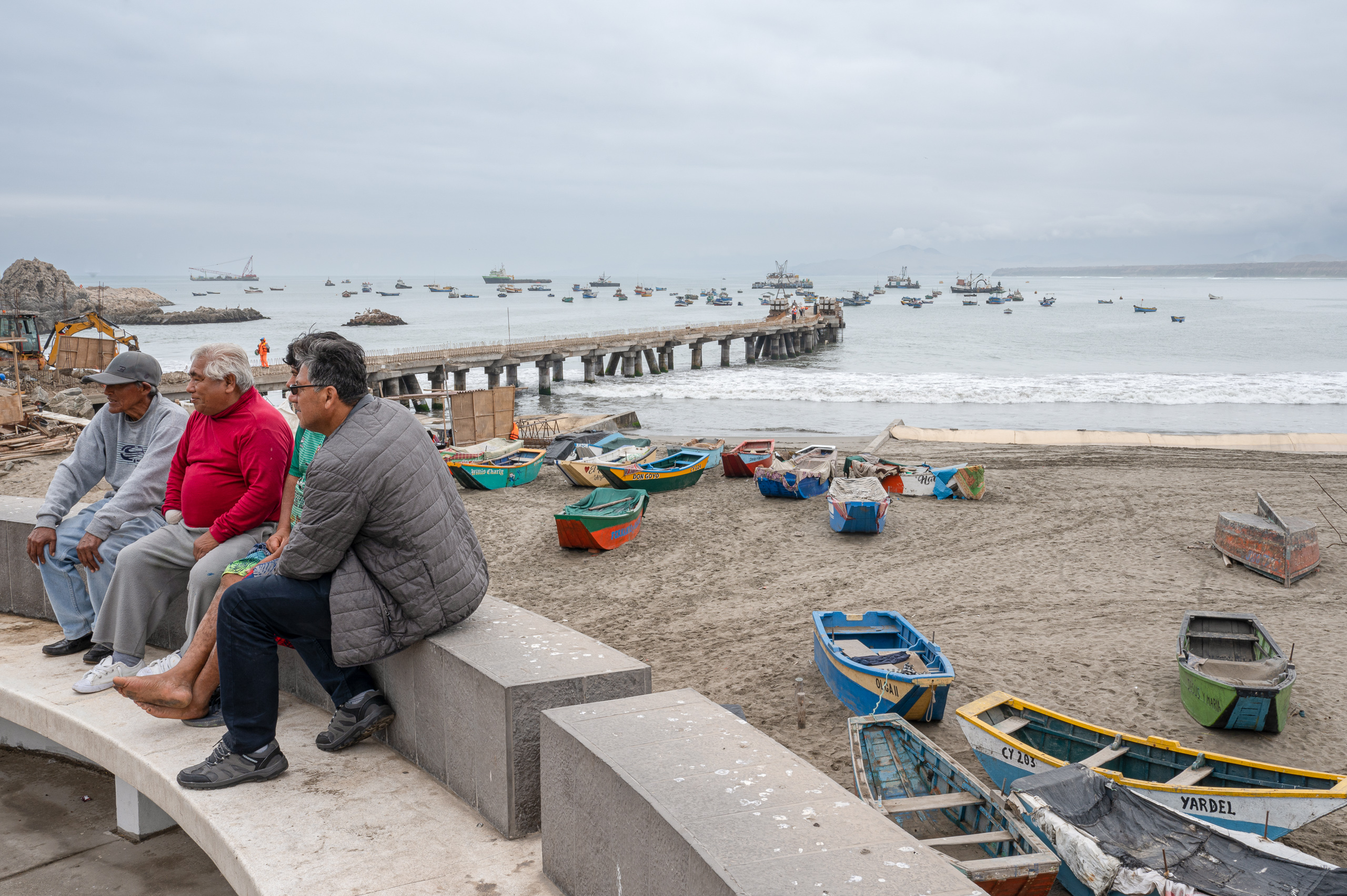 group of men sitting on concrete structure on beach 