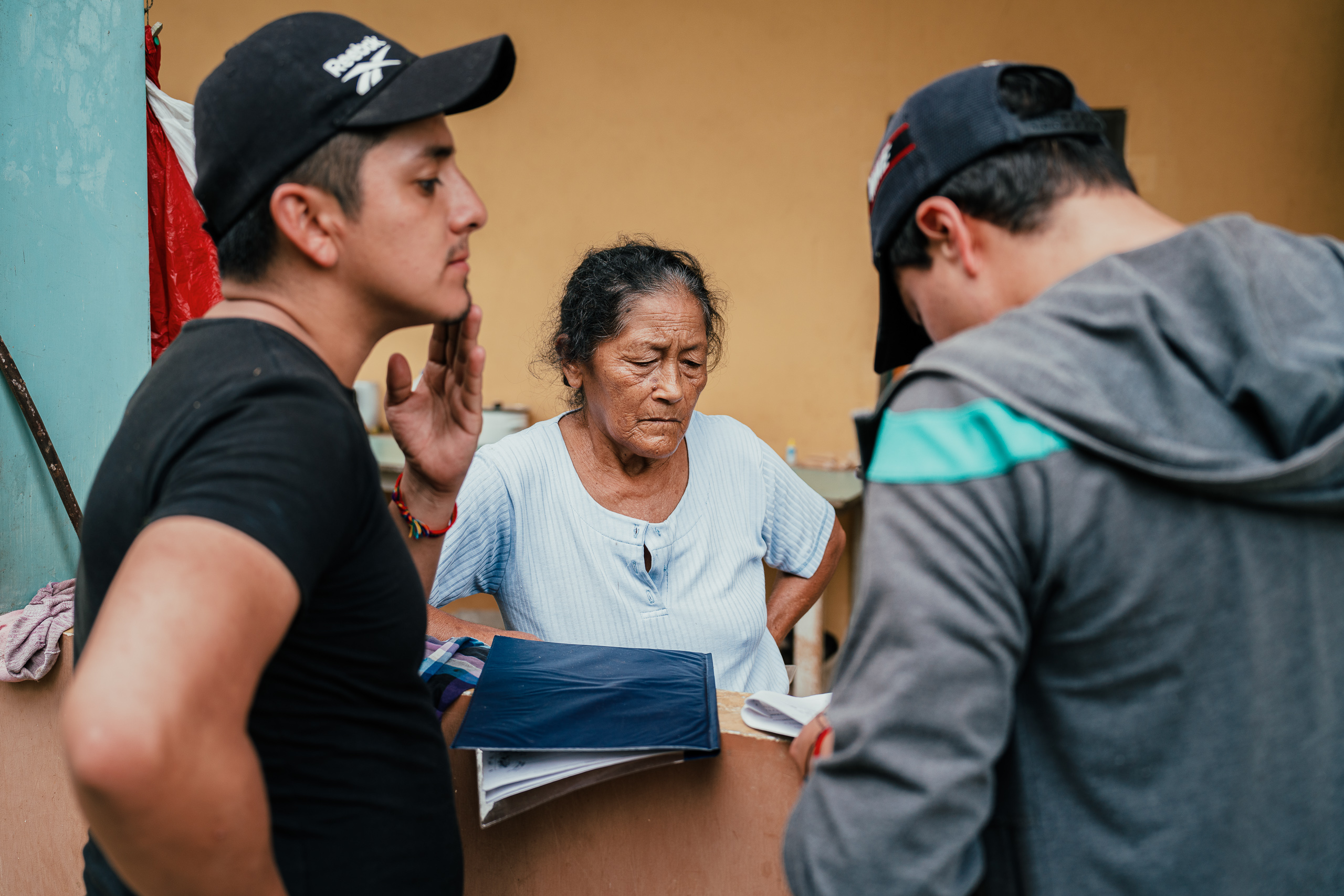 una mujer sosteniendo papeles frente a dos hombres
