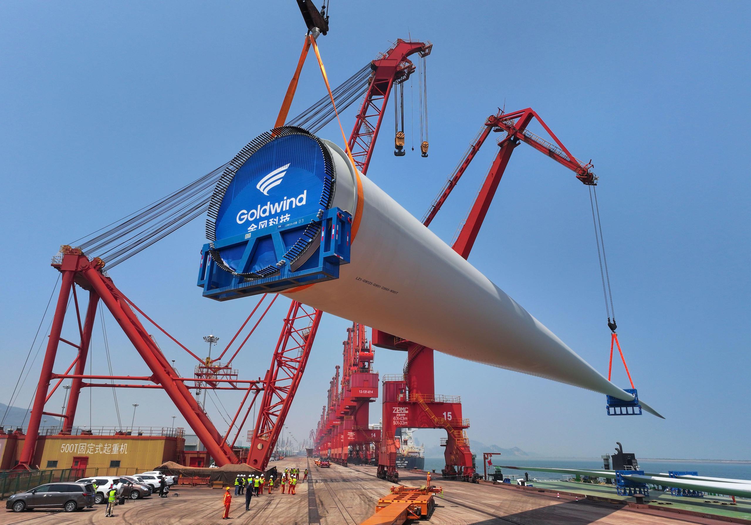 <p>今年6月，江苏省连云港市，工人正在把一扇123米长的风力涡轮机叶片吊装到船上。图片来源：Alamy</p>