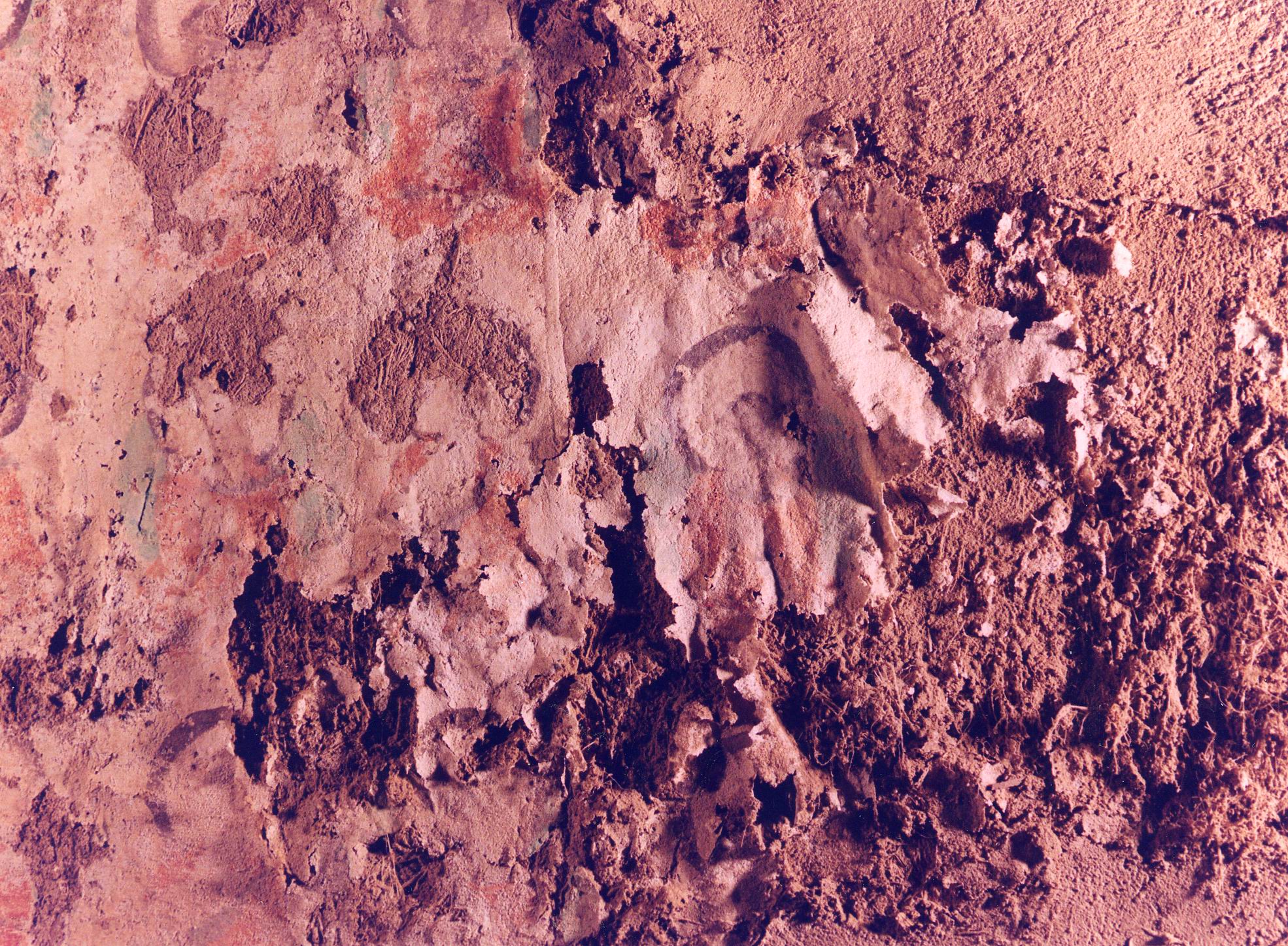 Plaster flaking off a red wall, painting underneath
