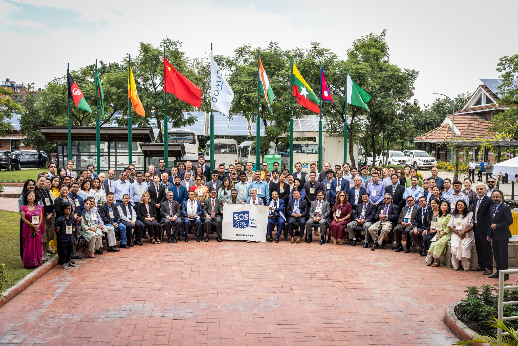 Large group of people posing for a photograph in front of country flags
