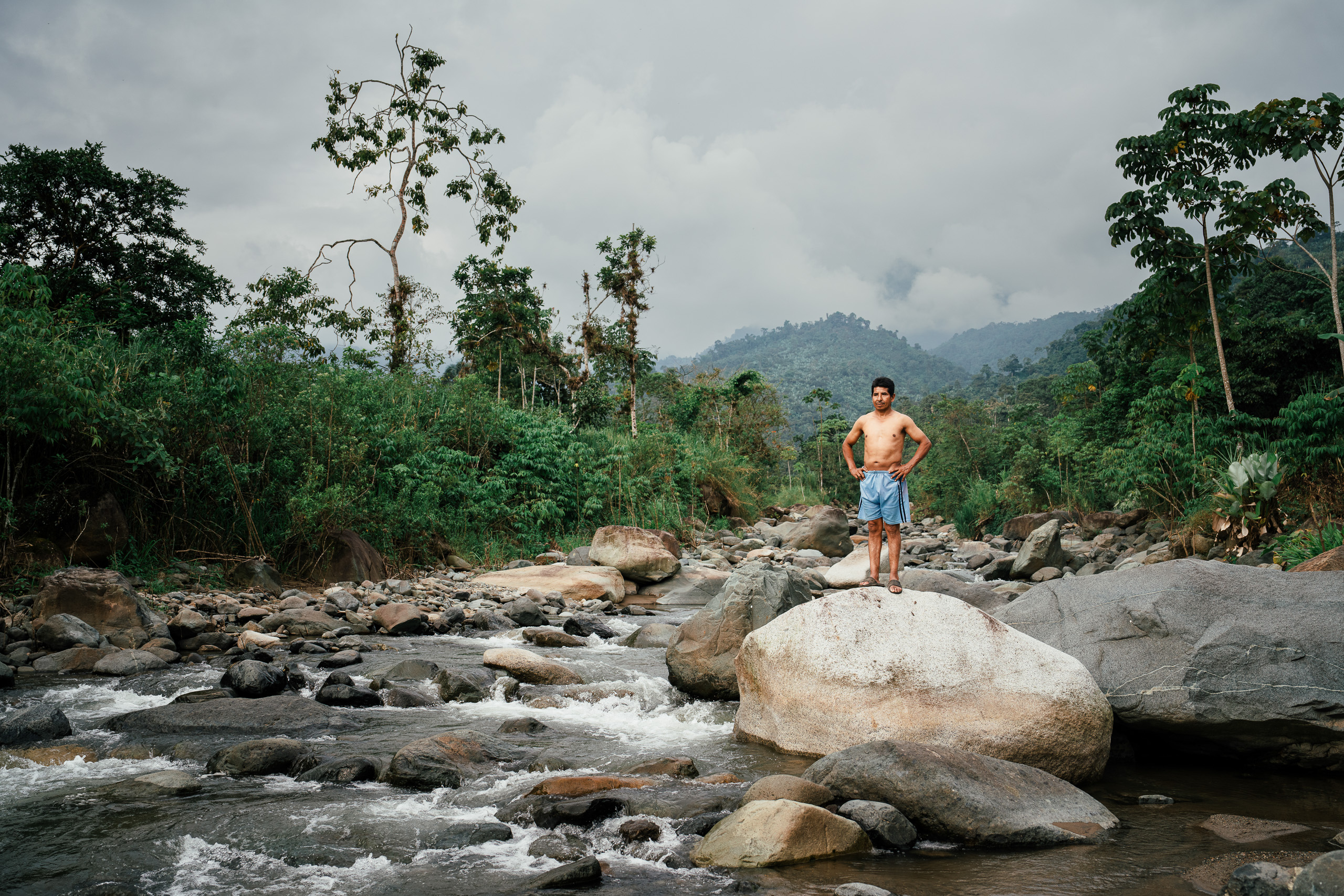 man standing on large rock in river
