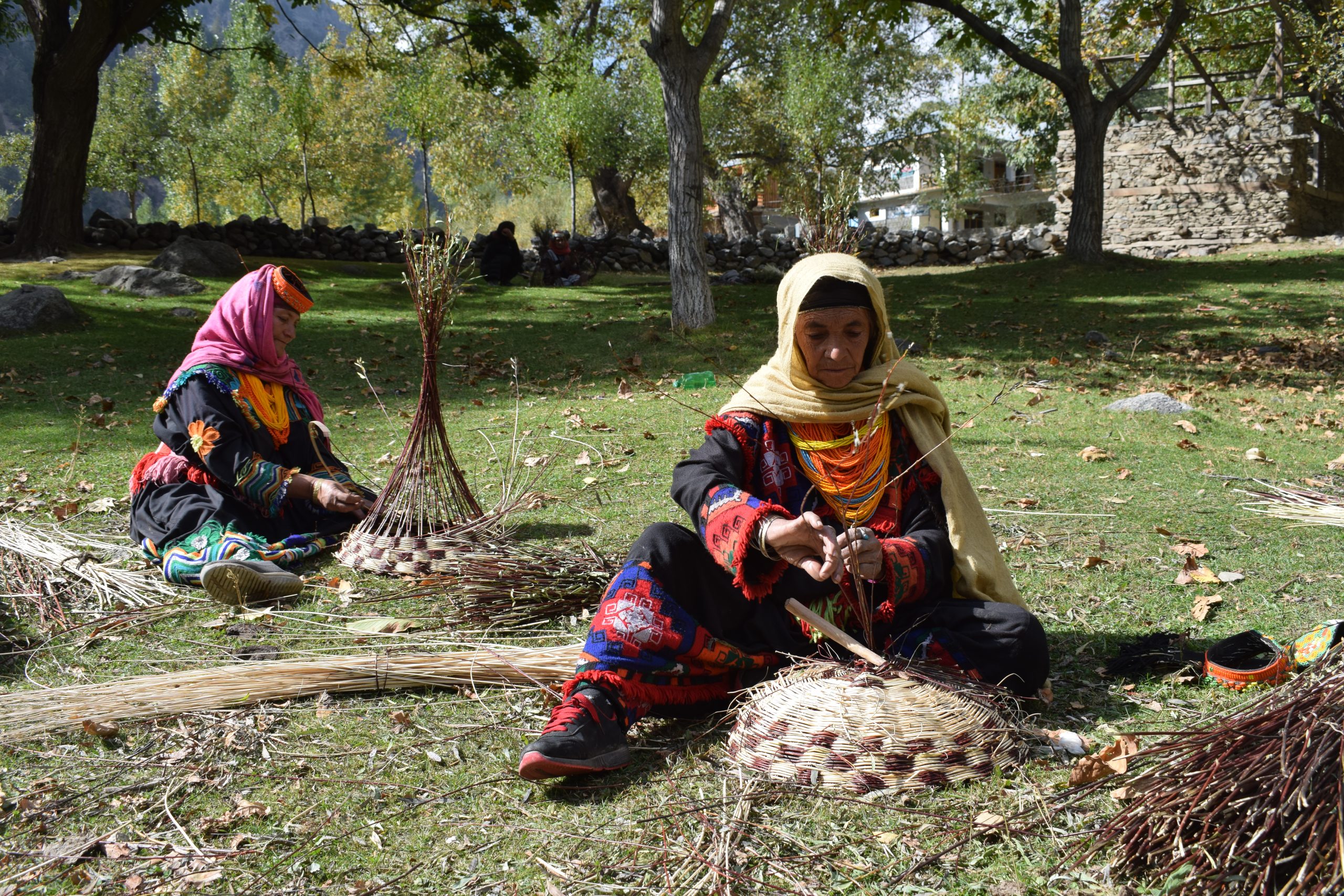women sitting on ground crafting straw objects