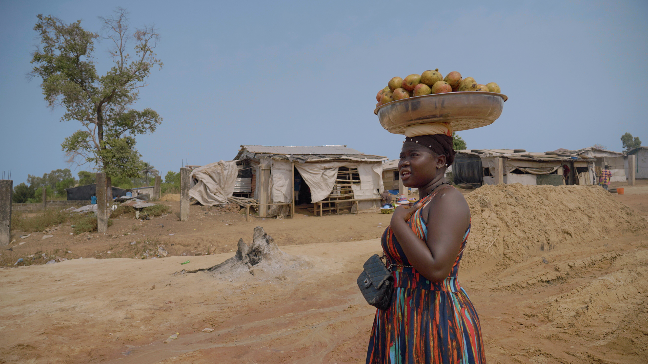 woman carrying vessel of mangoes on her head