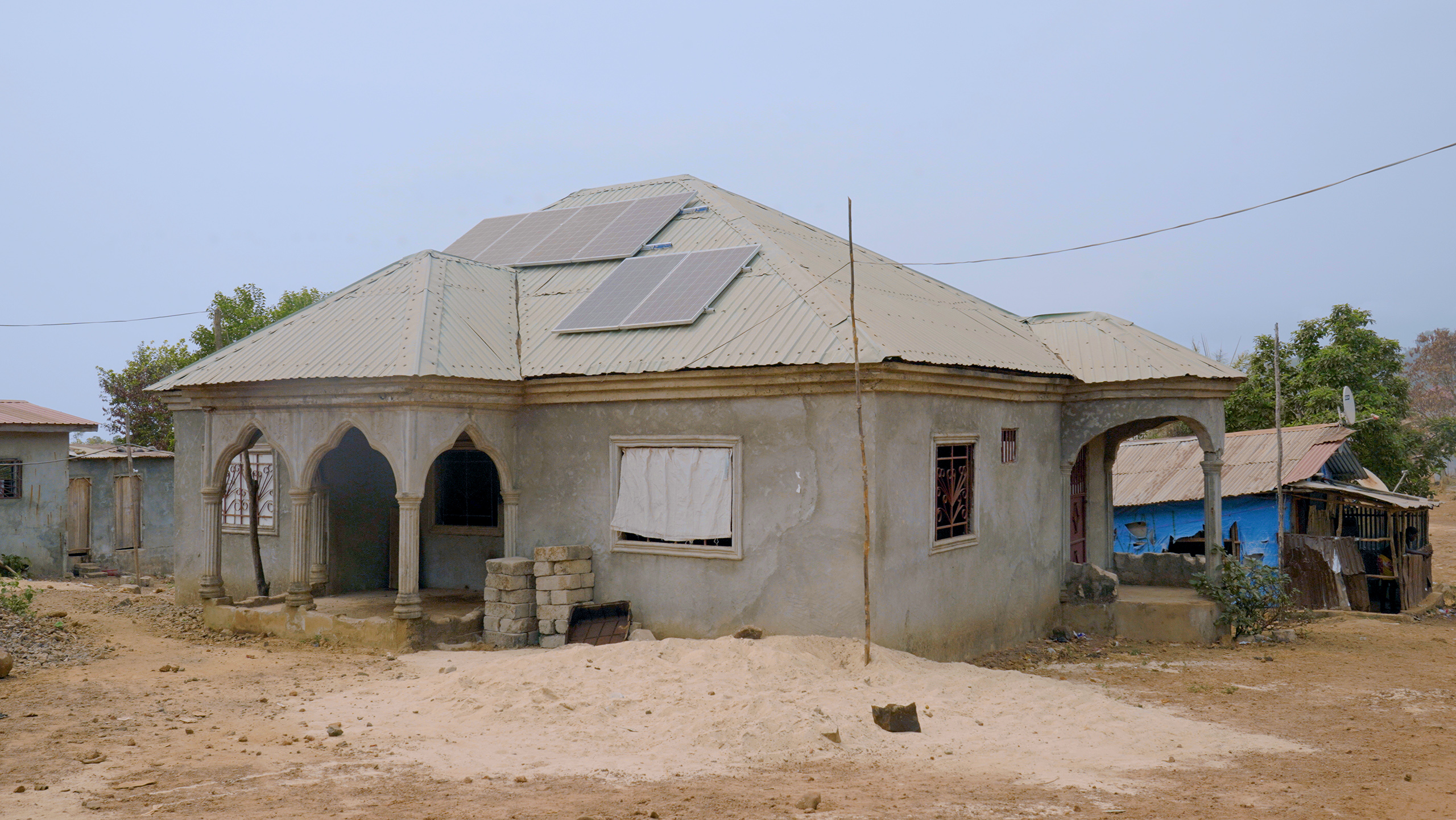 unpainted concrete house with solar panels on metal sheeting roof
