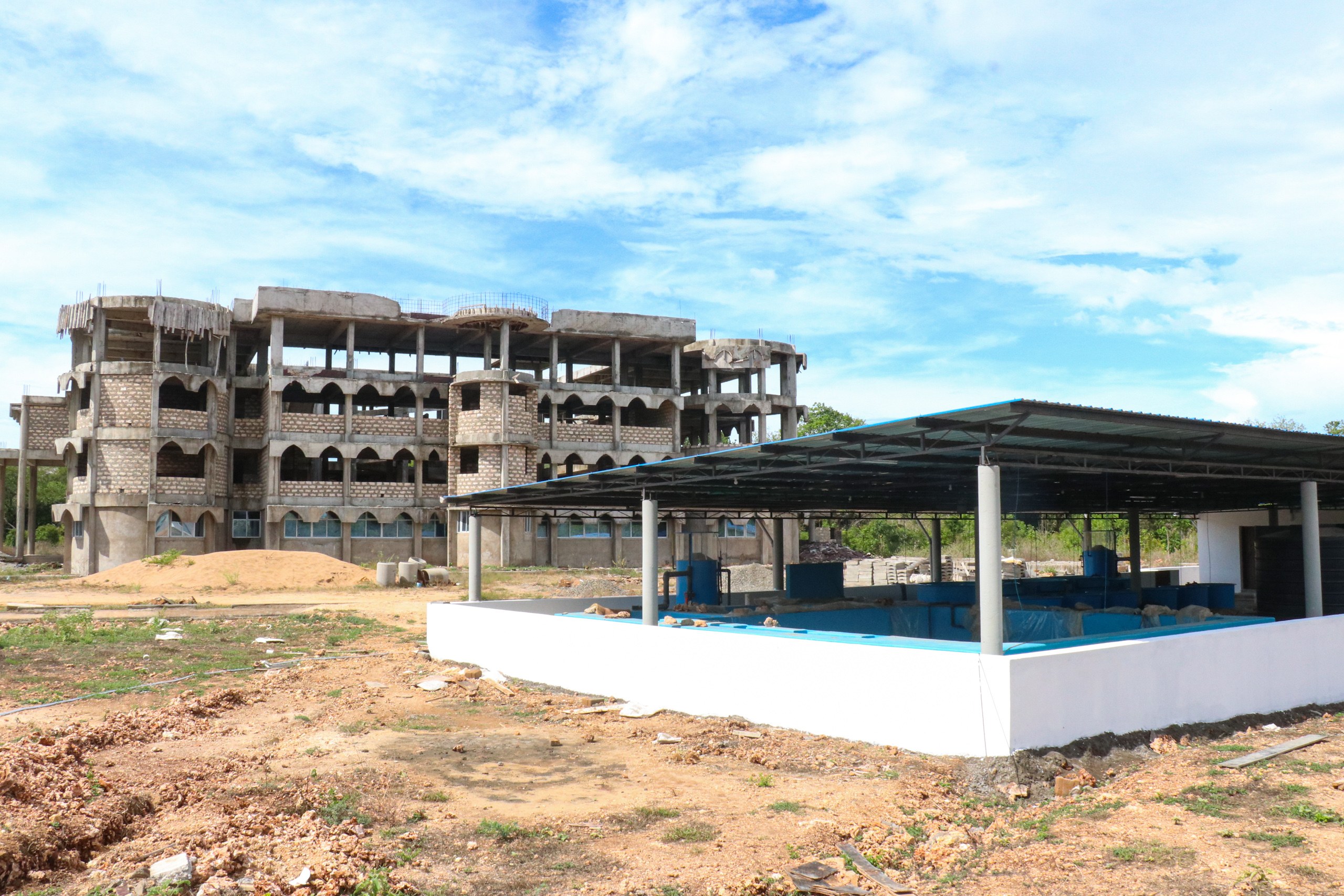 A concrete building under construction, low white building in foreground