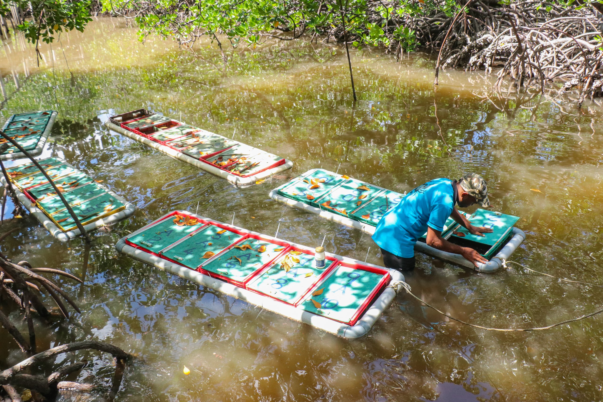 Man stood in a murky river next to several rafts