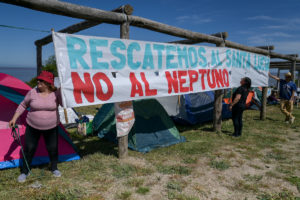 Protesters hold a large white banner with blue and red text