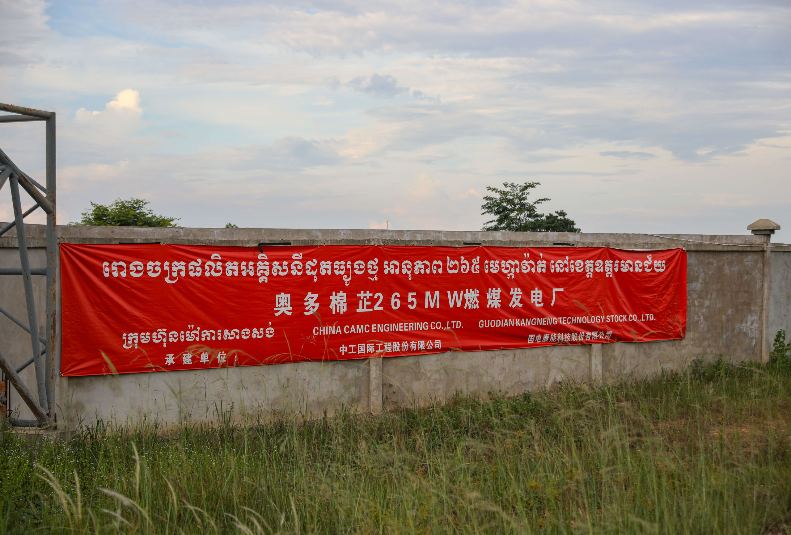 Red banner pinned to a wall with Chinese and Khmer script on