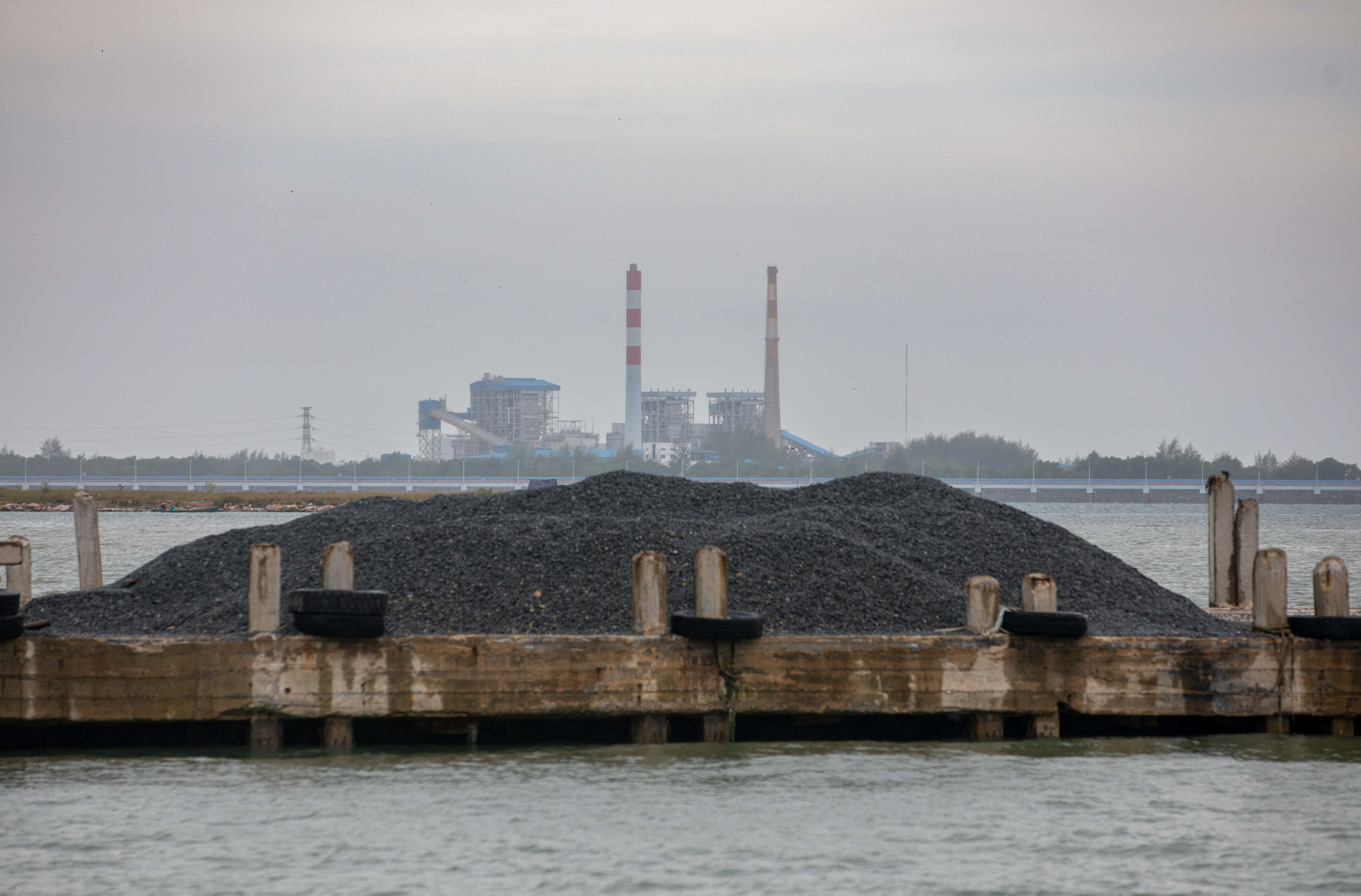 Piles of coal on a dock with a power station in the background