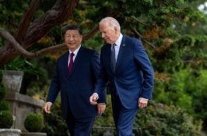 Joe Biden and Xi Jinping walk past trees, talking