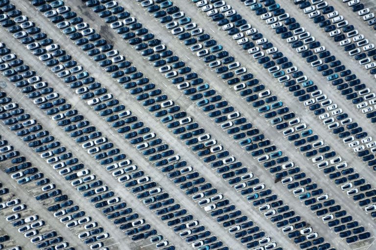 Bird's eye view of hundreds of cars in neat lines in a car park