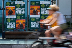 una persona en bicicleta pasa junto a una pared llena de carteles