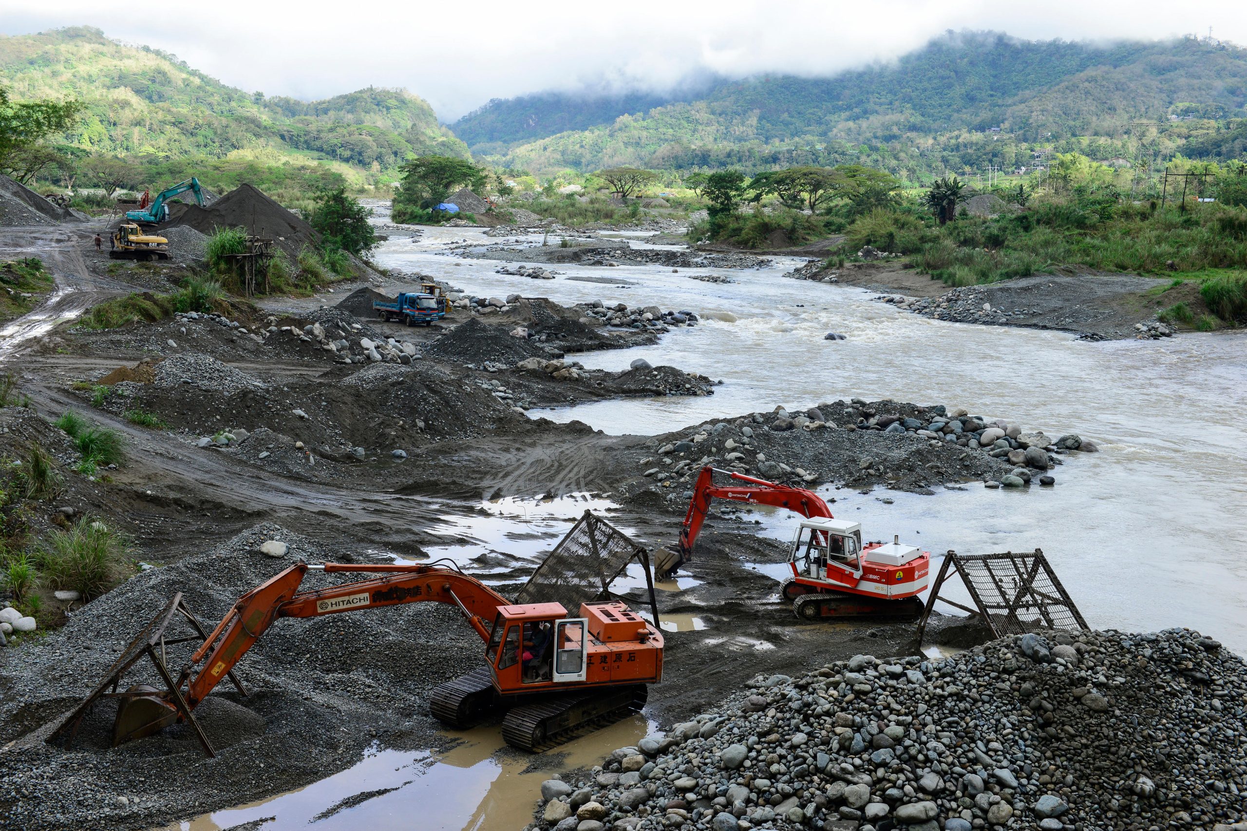 Backhoes digging sand near river