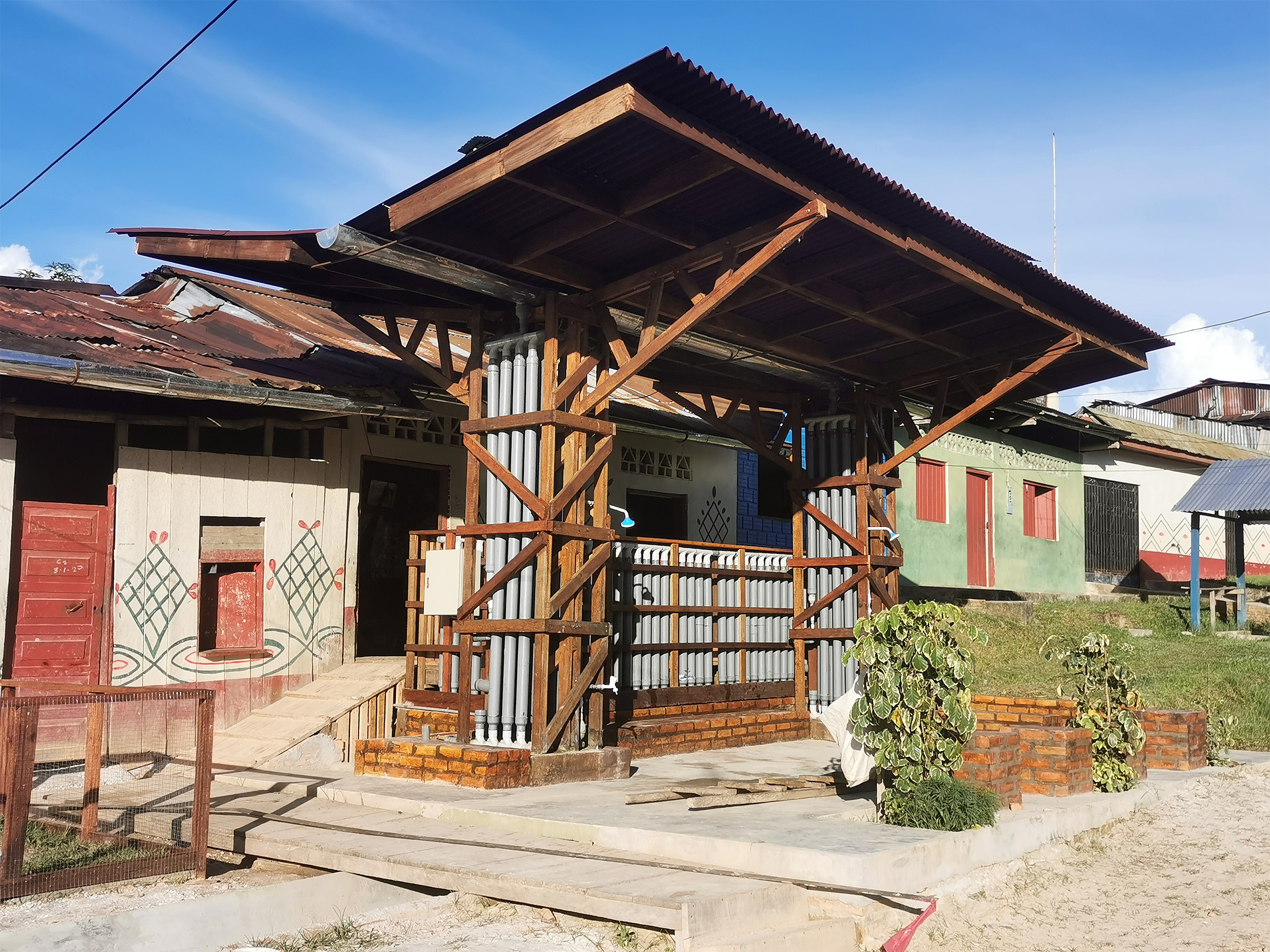 wooden structure with dual sloped roof in front of row of buildings