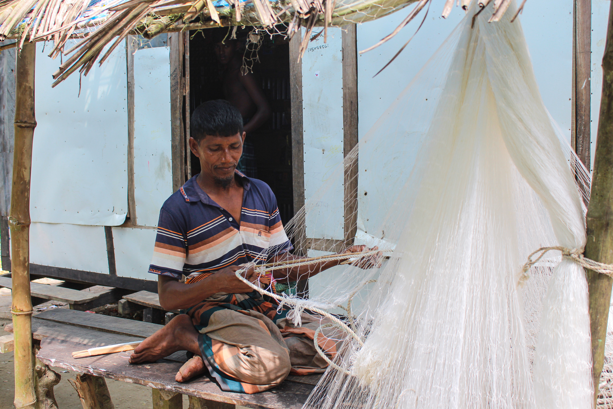 sitting man untangling fishing net