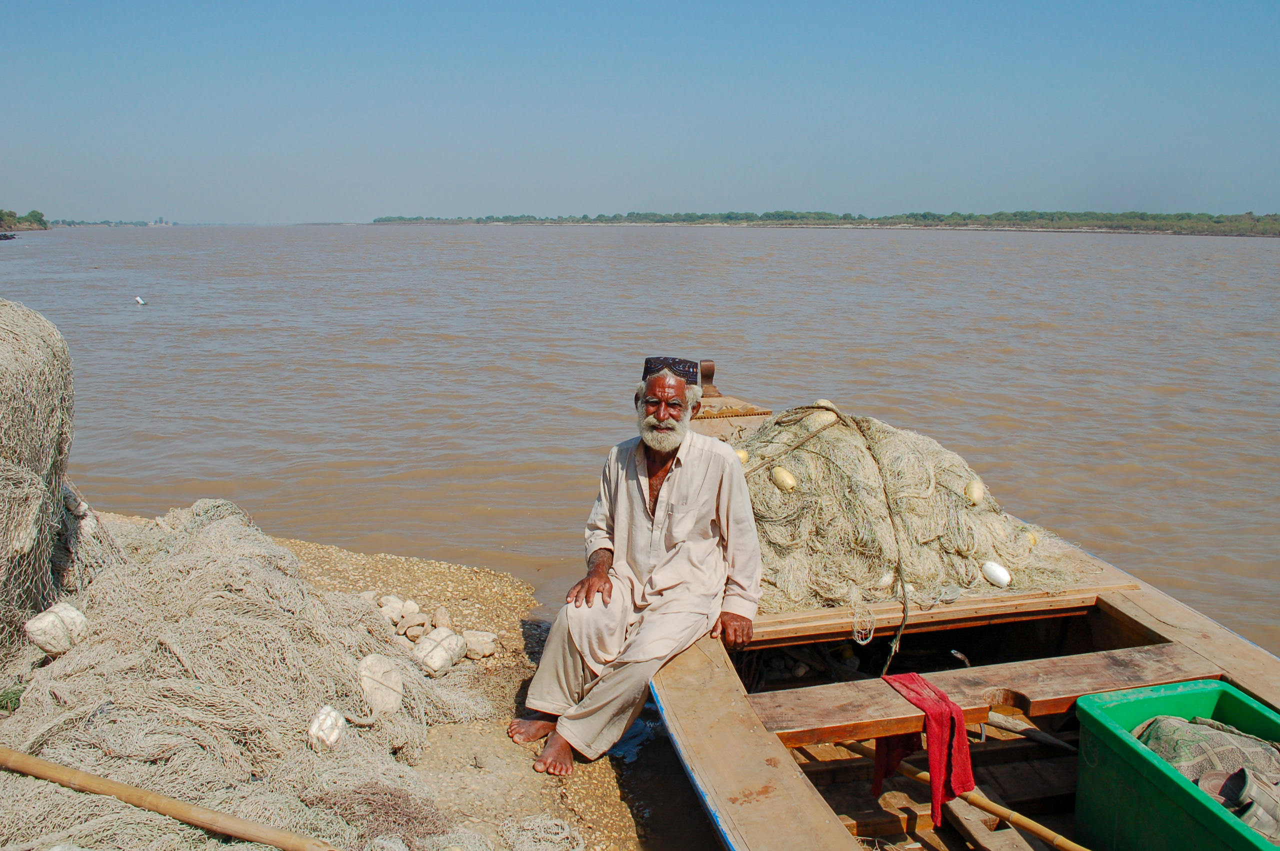 Man sitting on the edge of a boat floating on a river bank