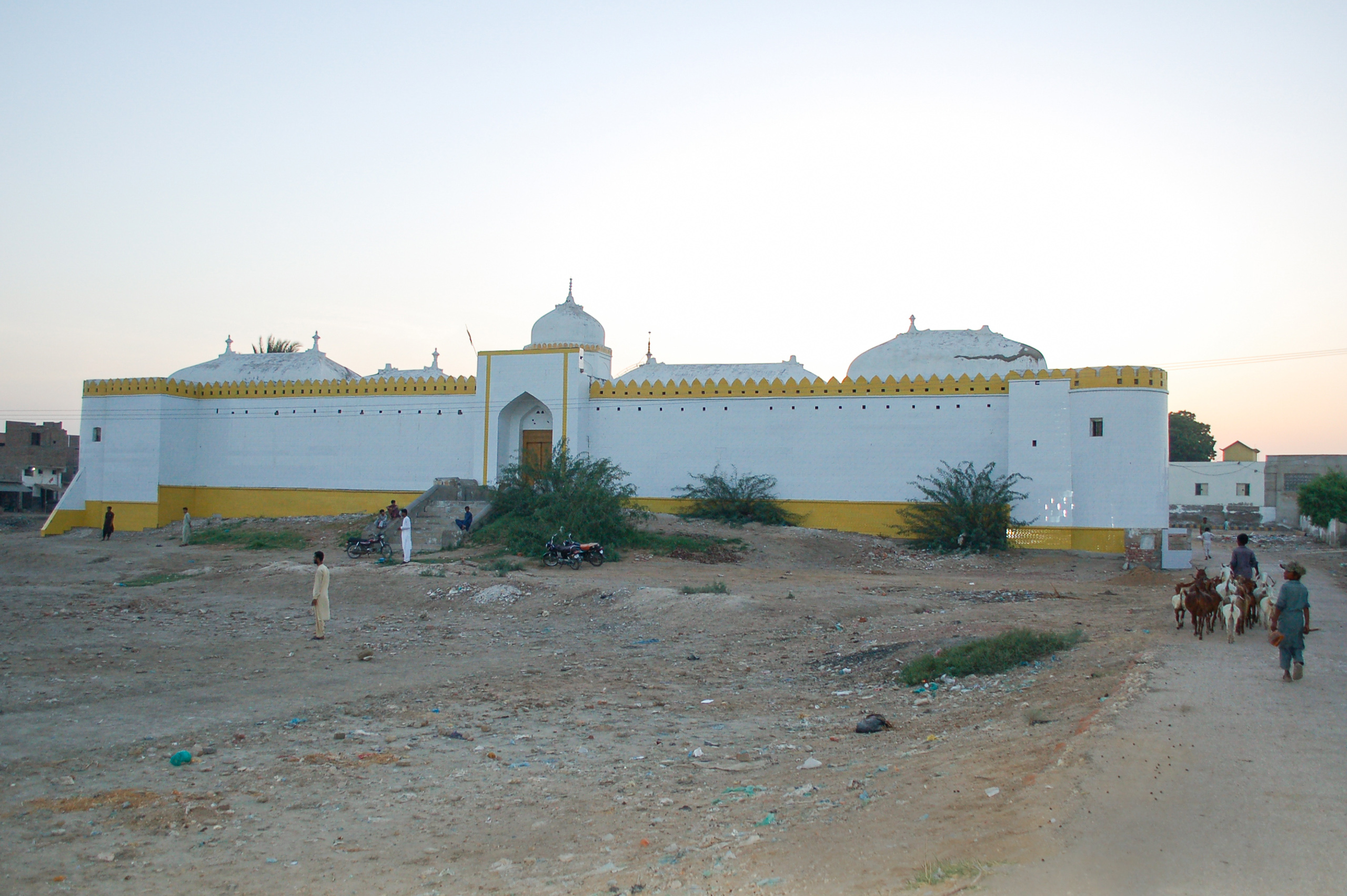 A white building in a sandy landscape, setting sun in background
