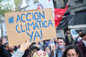 Un cartel con la frase "Acción climática ya" sostenido por una persona entre una multitud de manifestantes