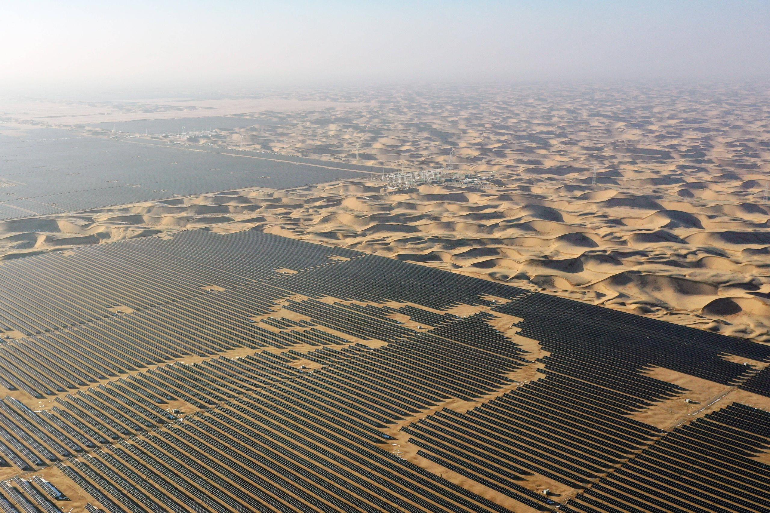 Aerial view of a solar farm next to desert sand dunes