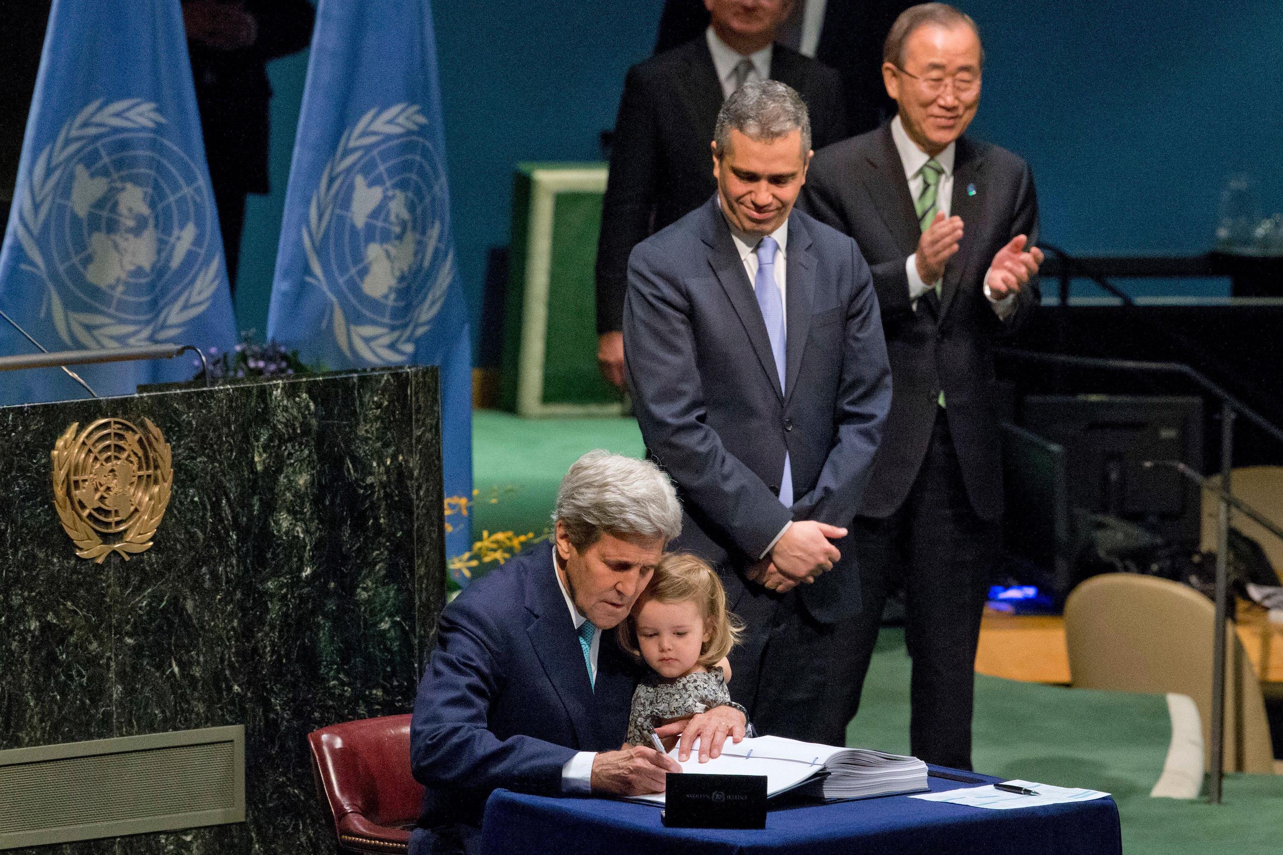 John Kerry holds his granddaughter as he signs the Paris Agreement