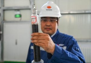 a person wearing a hard hat holding a tube with liquid