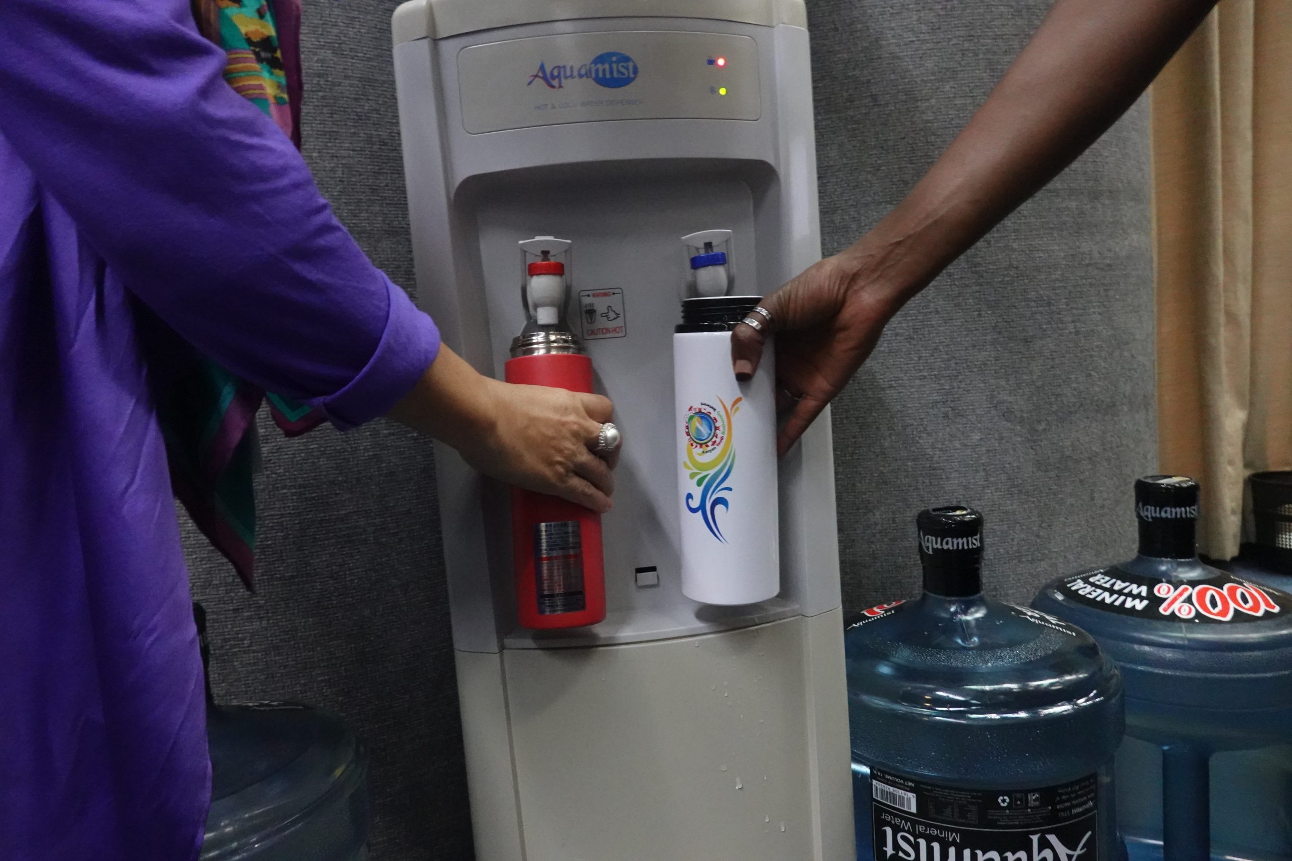 two people refilling water bottles