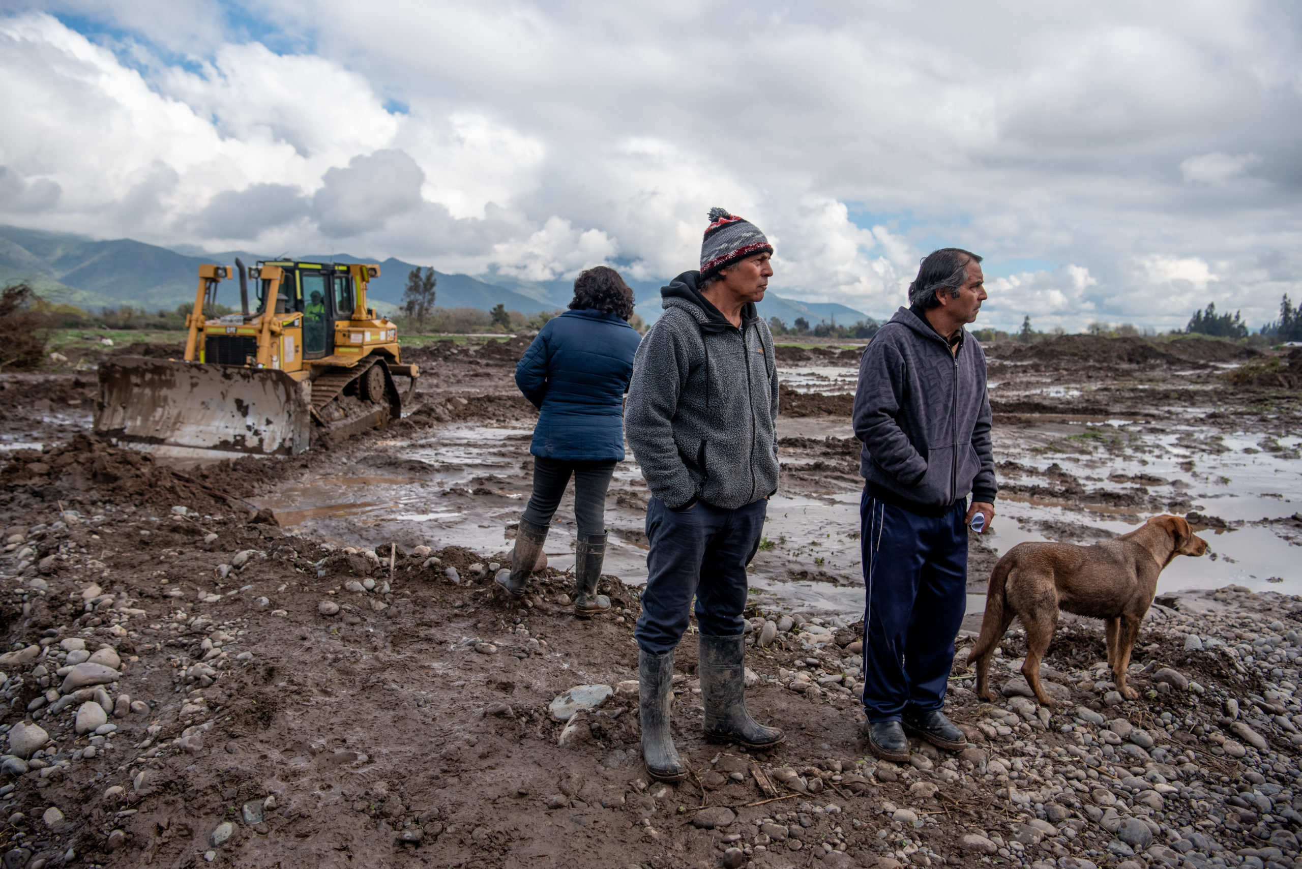 tres personas y un perro en un campo embarrado