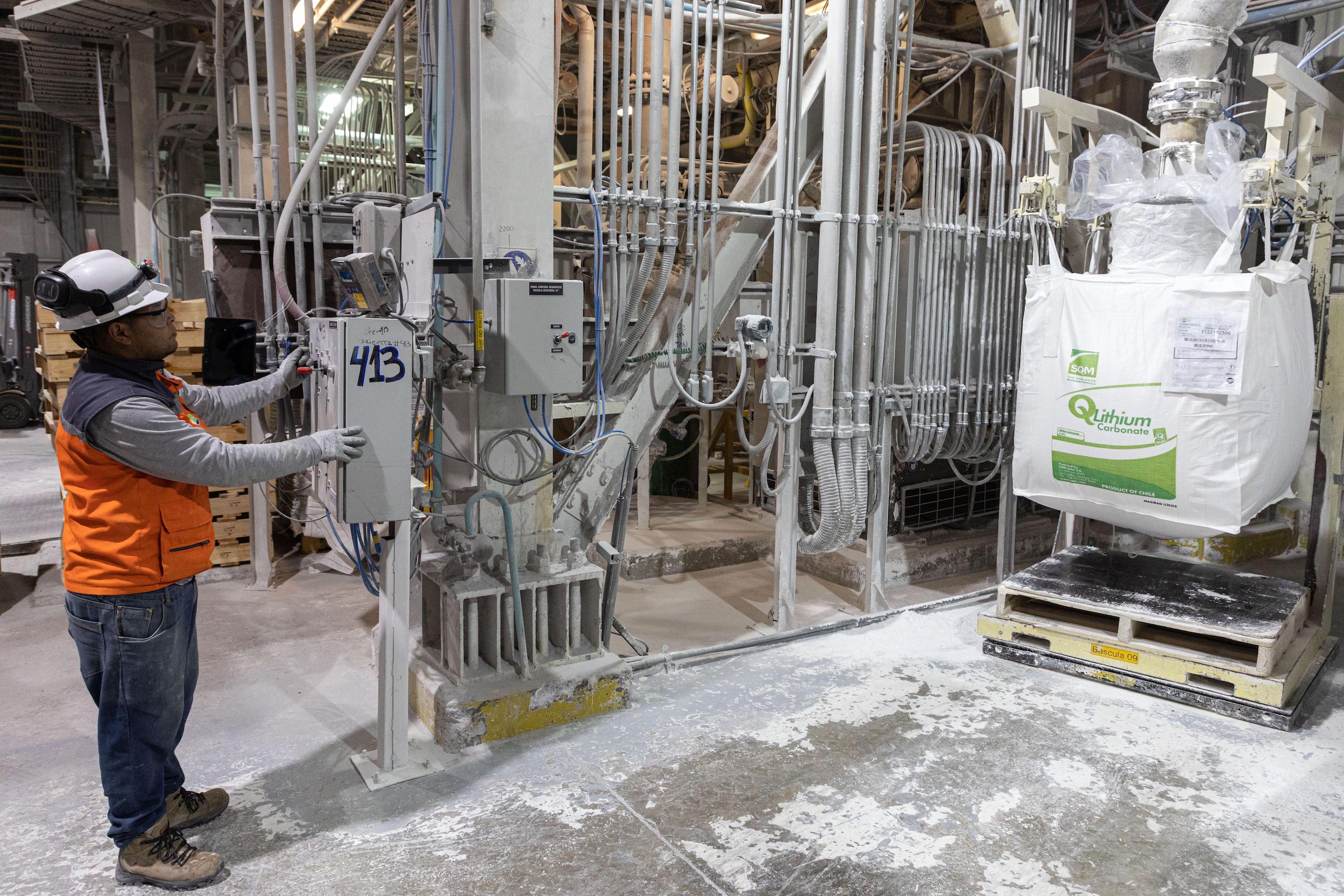 Una persona con casco al lado de una máquina en una fábrica de carbonato de litio