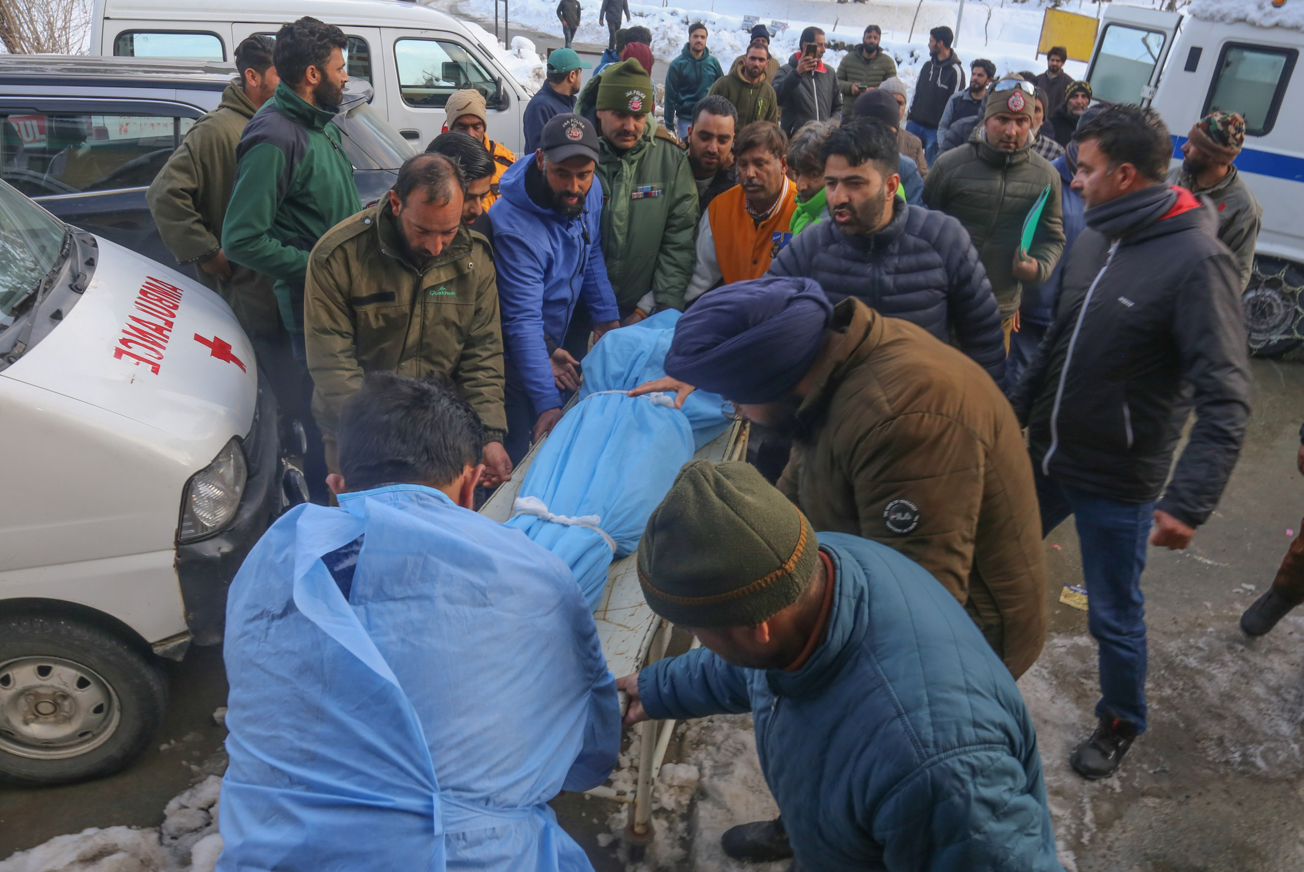 A crowd of people around a blue body bag