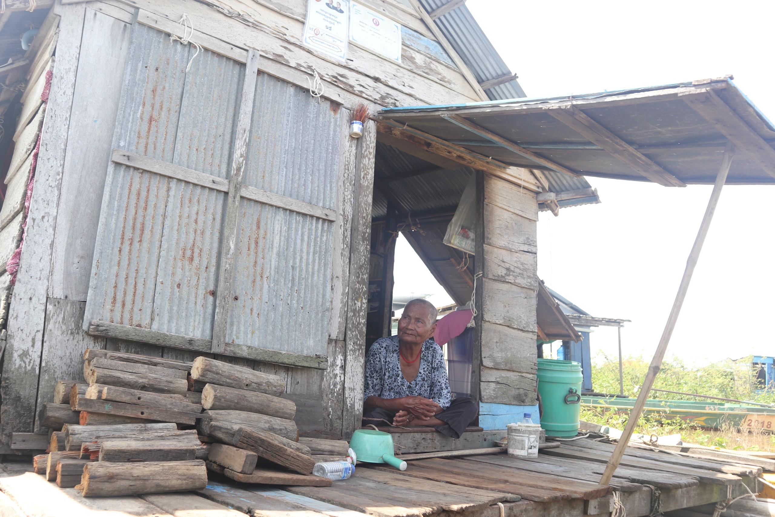 A woman looking out from the front door of a small makeshift house