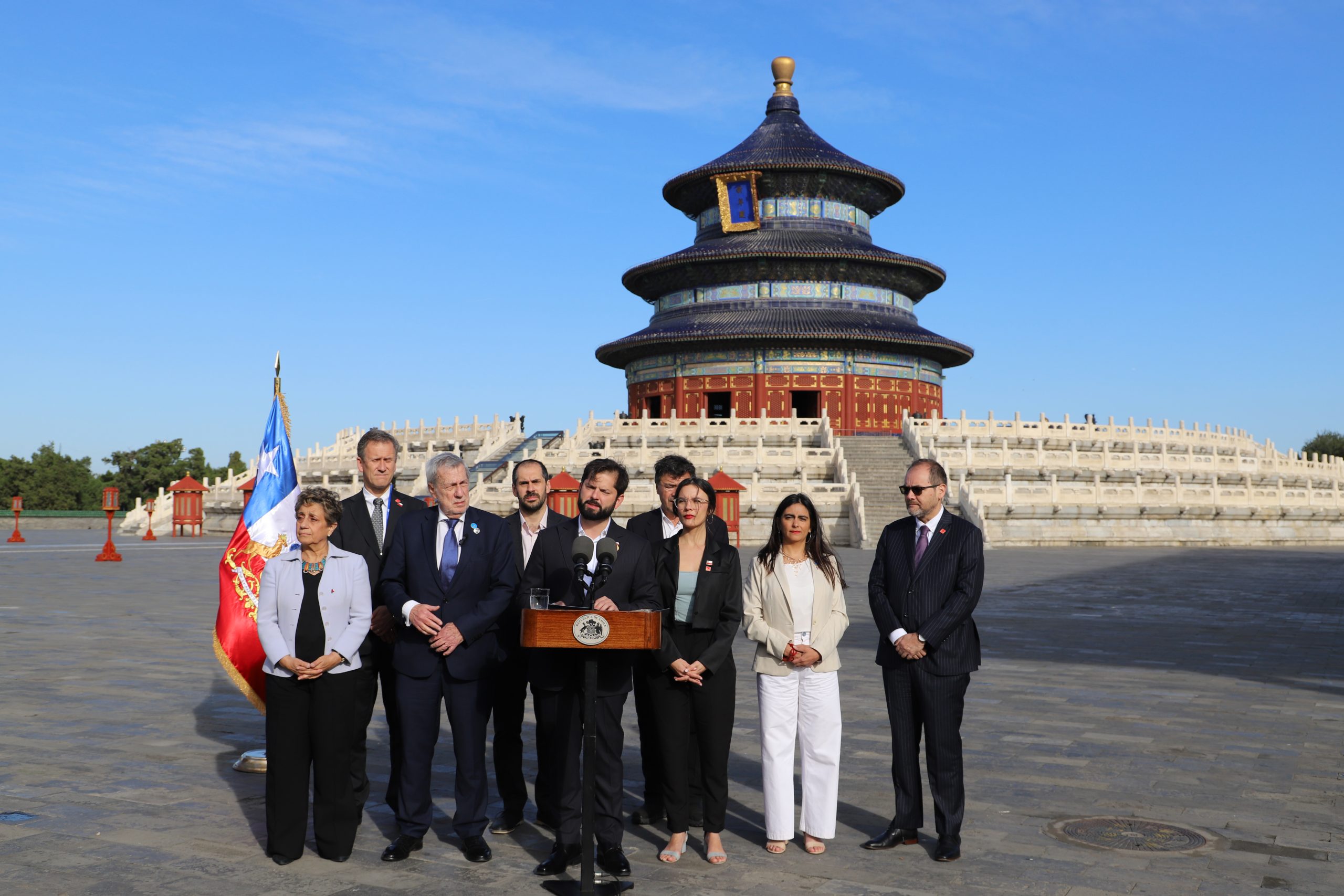 Group of people in suits standing behind lectern in outdoor square