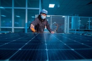 a person wearing a mask and working on a production line of solar panels