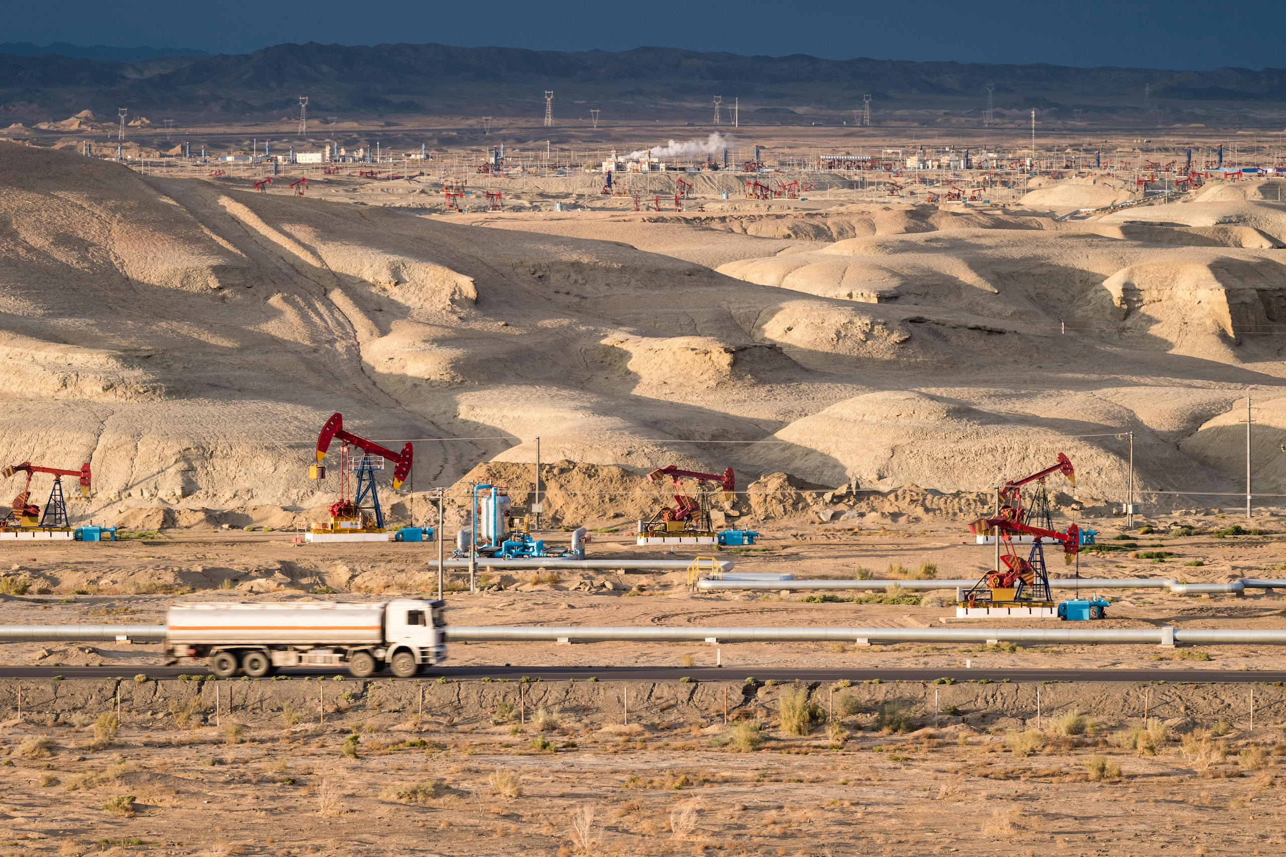 a truck driving through an oil drilling field in desert
